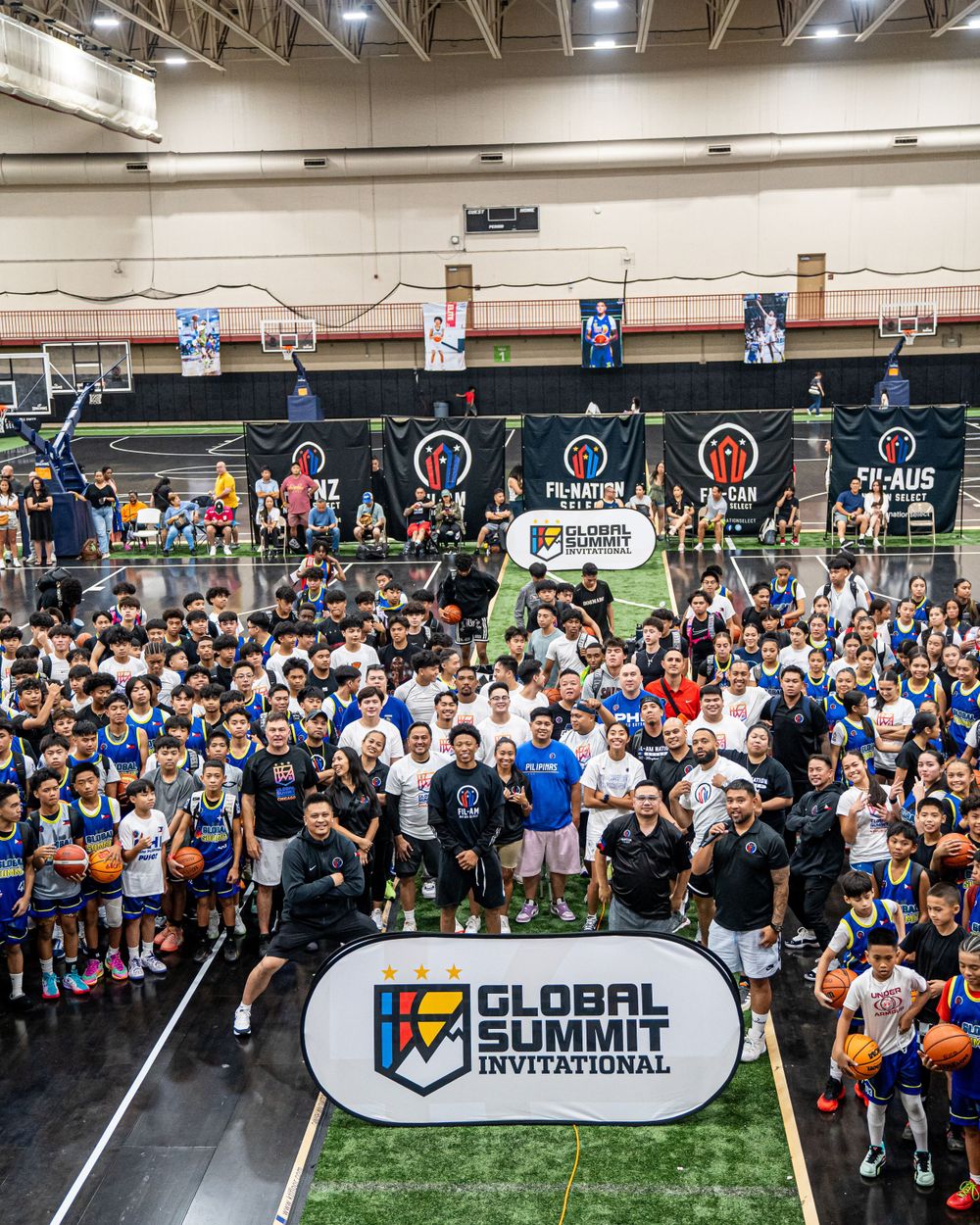 Large crowd gathers for Global Summit Invitational event in indoor sports facility.