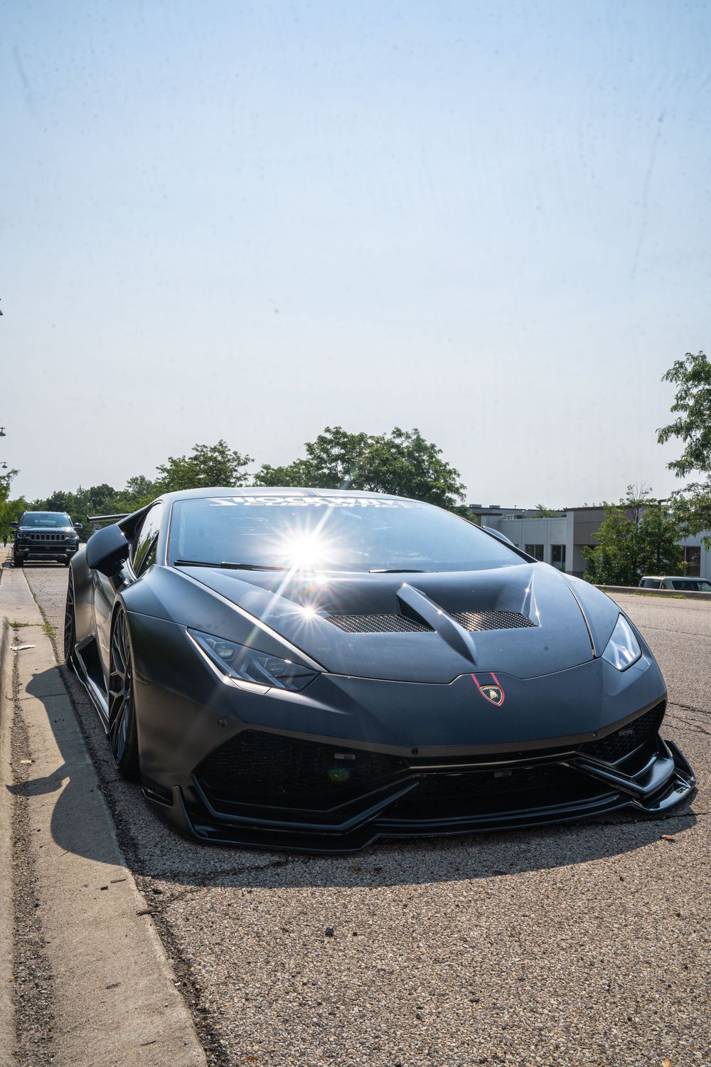 Black Lamborghini supercar gleams in sunlight with dramatic angular bodywork.