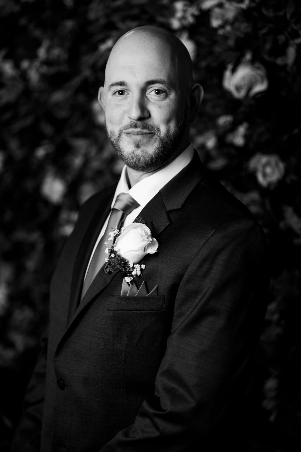 Wedding portrait against floral backdrop in black and white.