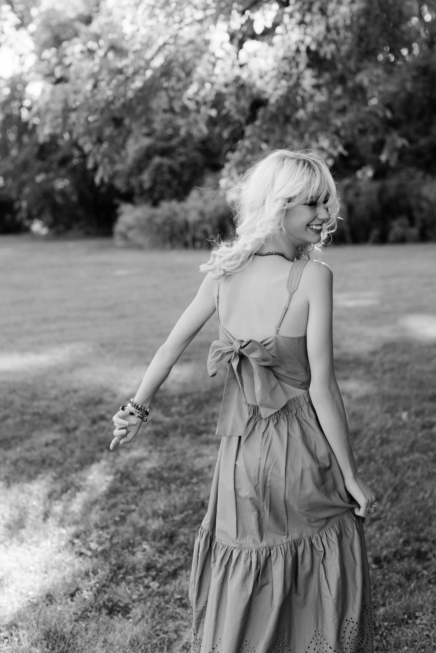 Black and white photo of woman in flowing dress dancing outdoors.