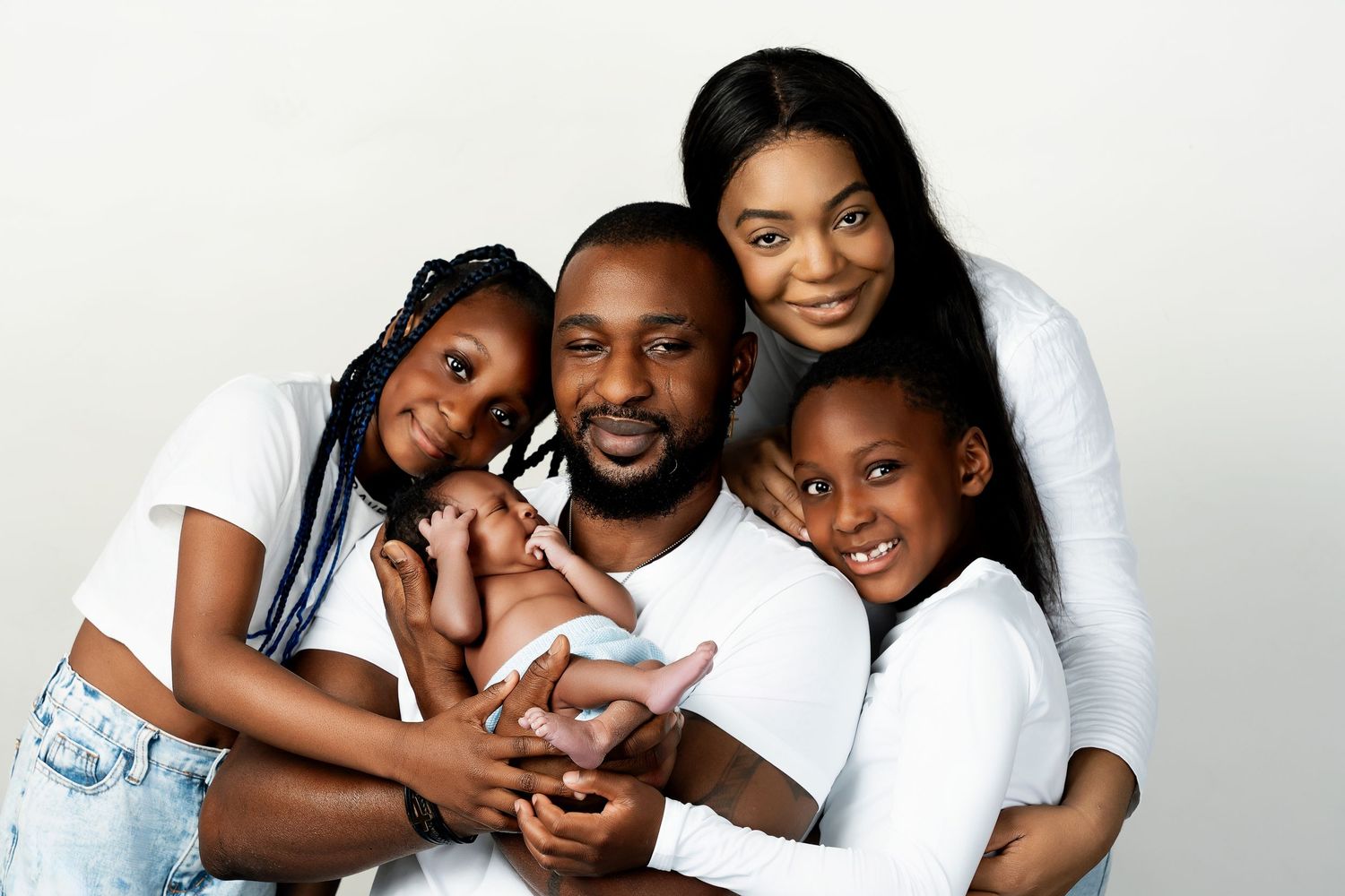 A loving family poses together in white shirts against a light background for a heartwarming portrait.