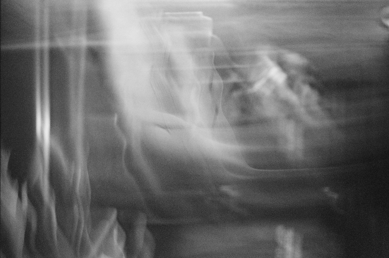 Abstract black and white blurred motion photograph with ghostly streaks of light and movement.