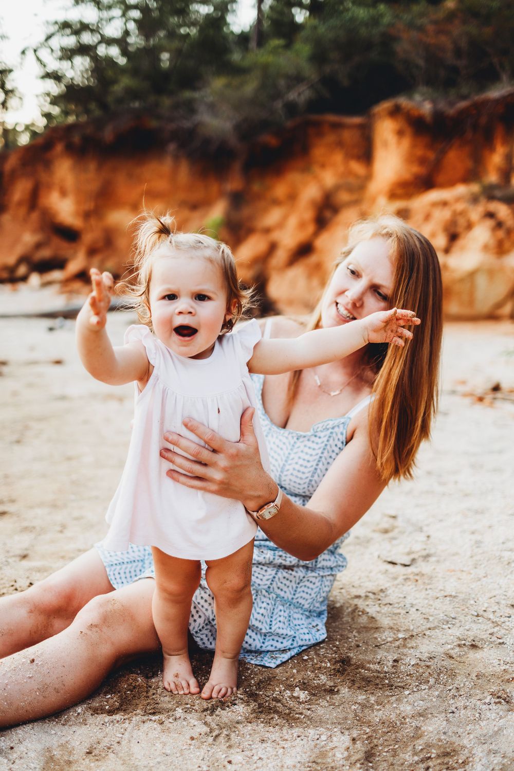 A sweet playtime moment on beach with orange cliffs behind.