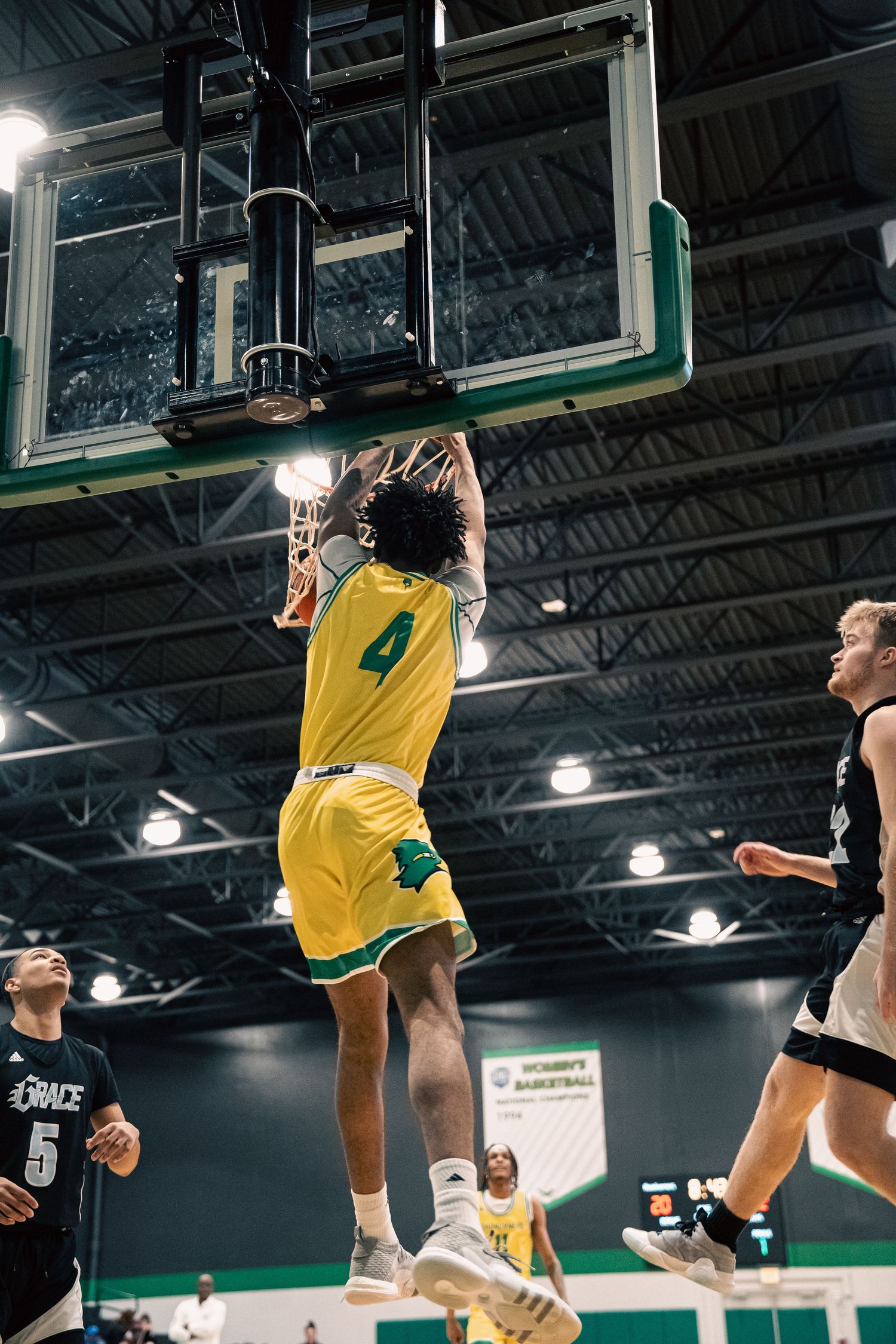 Player in yellow jersey attempts a slam dunk during basketball game.