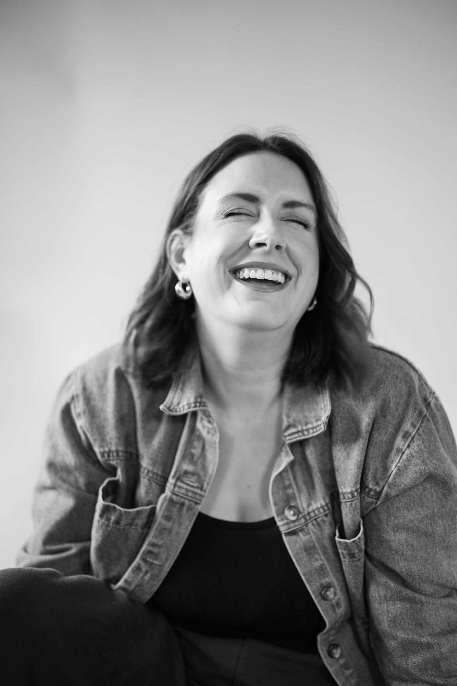 Black and white portrait of someone laughing while wearing denim jacket.