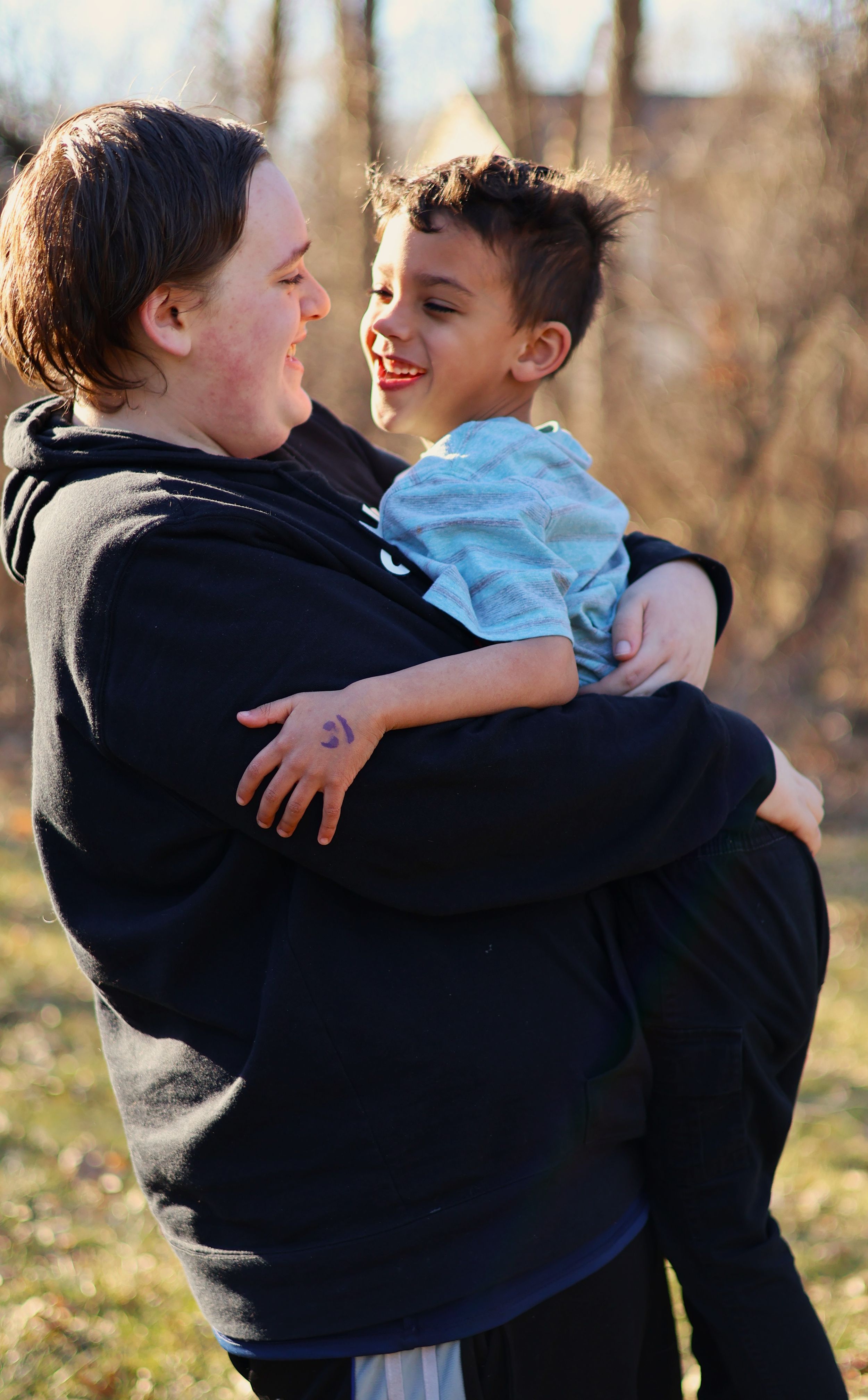 Candid moment of joy and laughter between two people embracing outdoors.