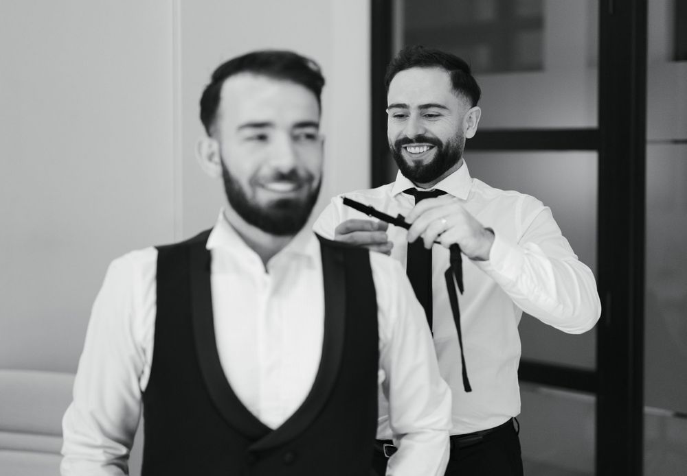 Two formally dressed people sharing a lighthearted moment in black and white.