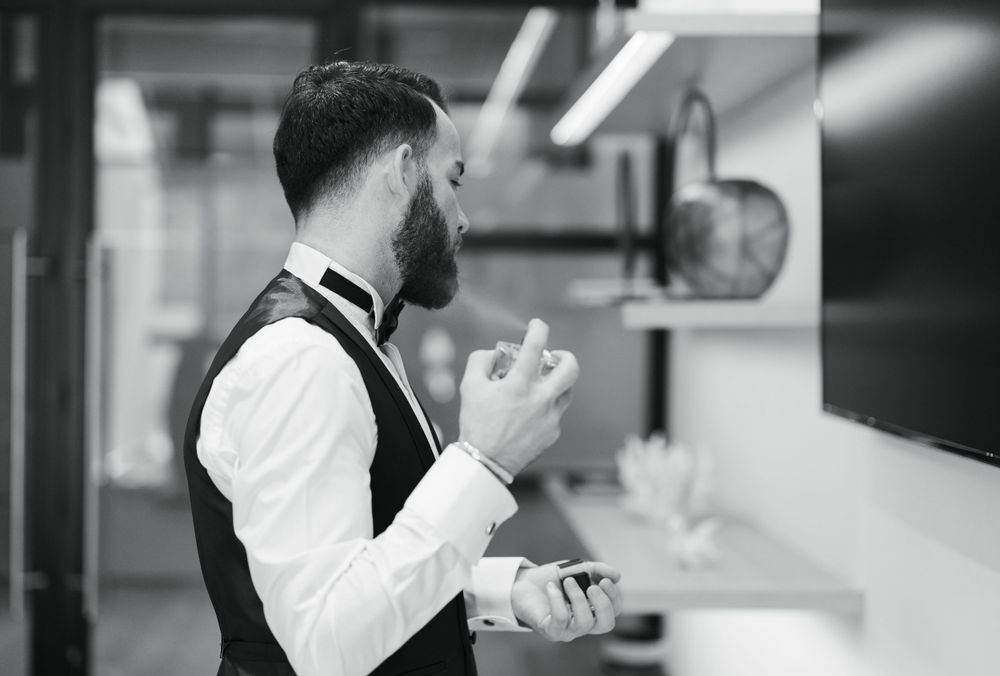 Side profile of formally dressed person adjusting cuffs in black and white.