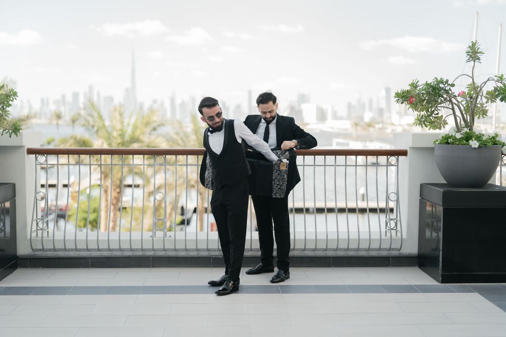 Two formal-dressed figures standing on balcony overlooking city skyline.