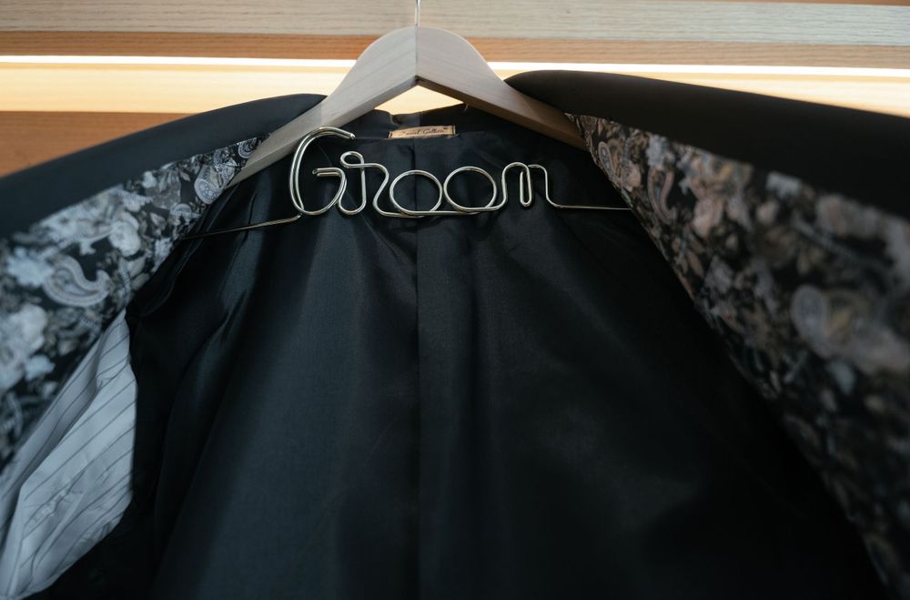 Wire hanger with 'Groom' text displaying formal black clothing.