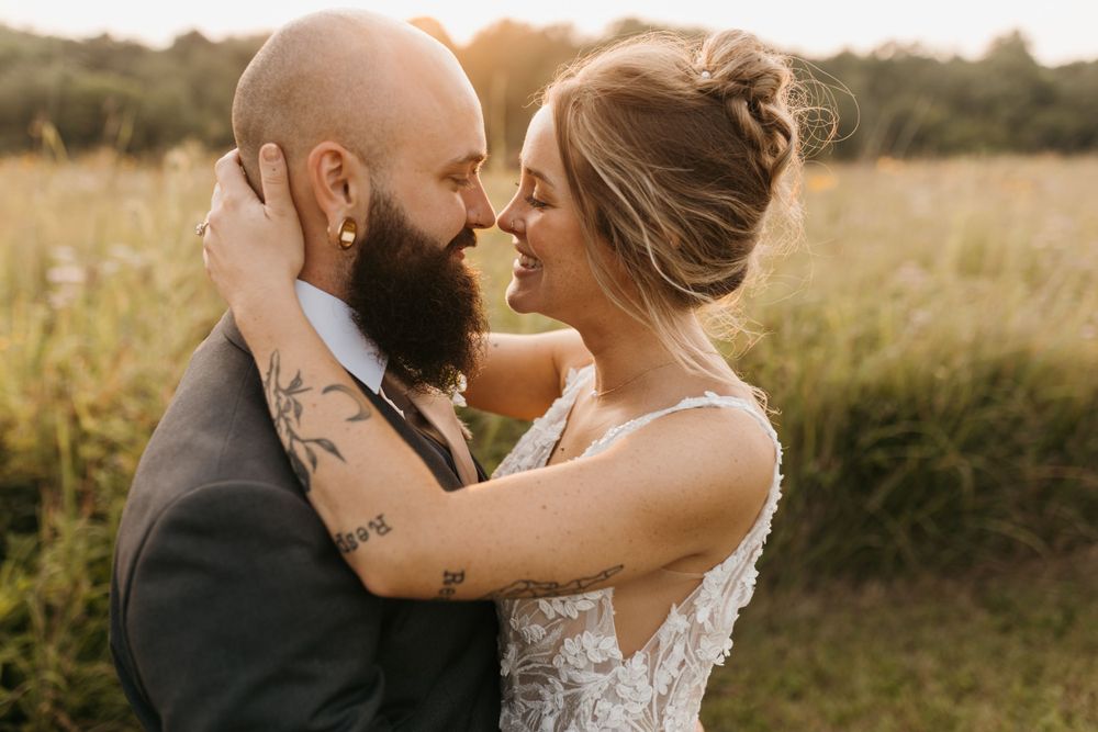 Bride and groom touching foreheads intimately in a golden meadow.