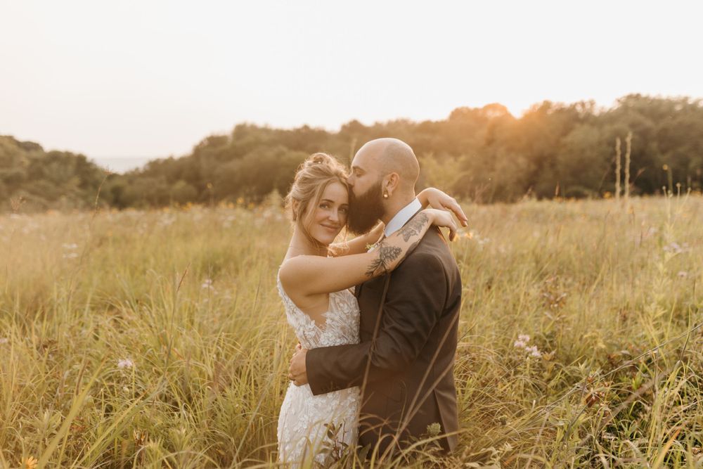 Couple sharing a warm embrace in a sunlit wildflower field.