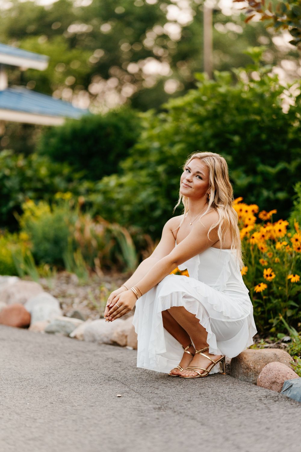 A summer portrait near colorful flowers with a white dress and sandals.