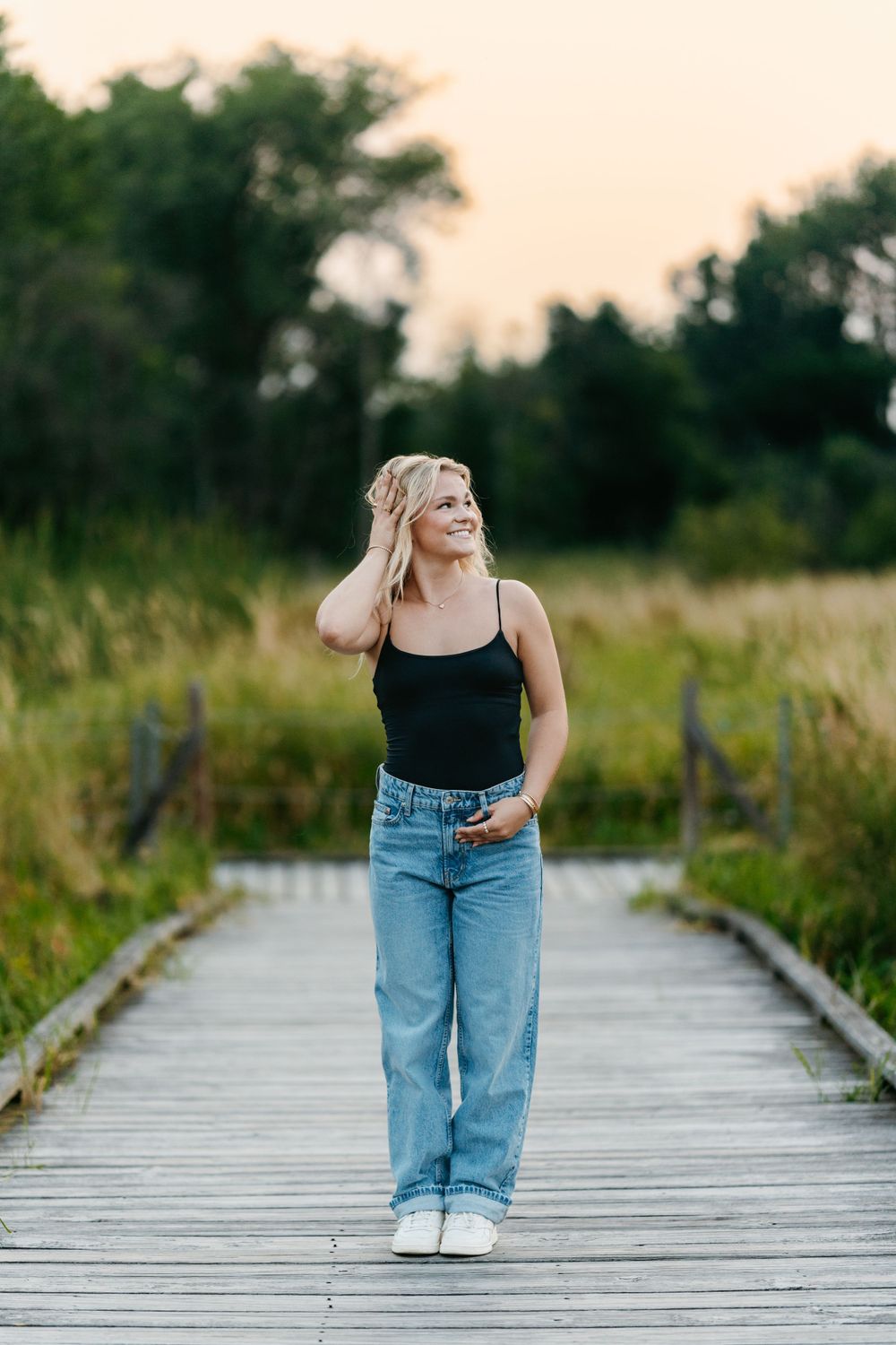 A casual summer look with jeans and tank top on a wooden boardwalk path.