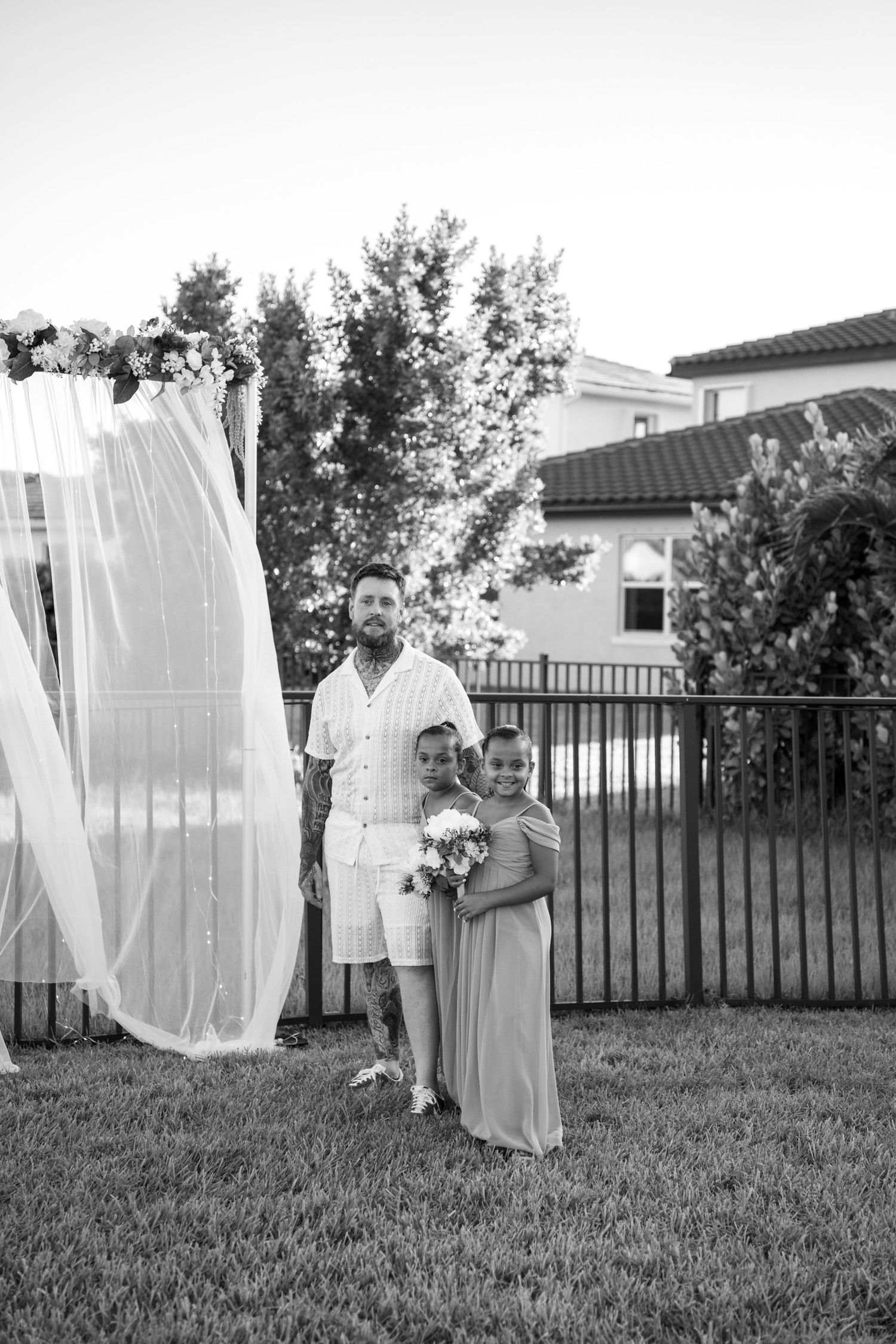 White laundry hanging to dry on clotheslines in a sunny backyard with green grass and wooden fence.