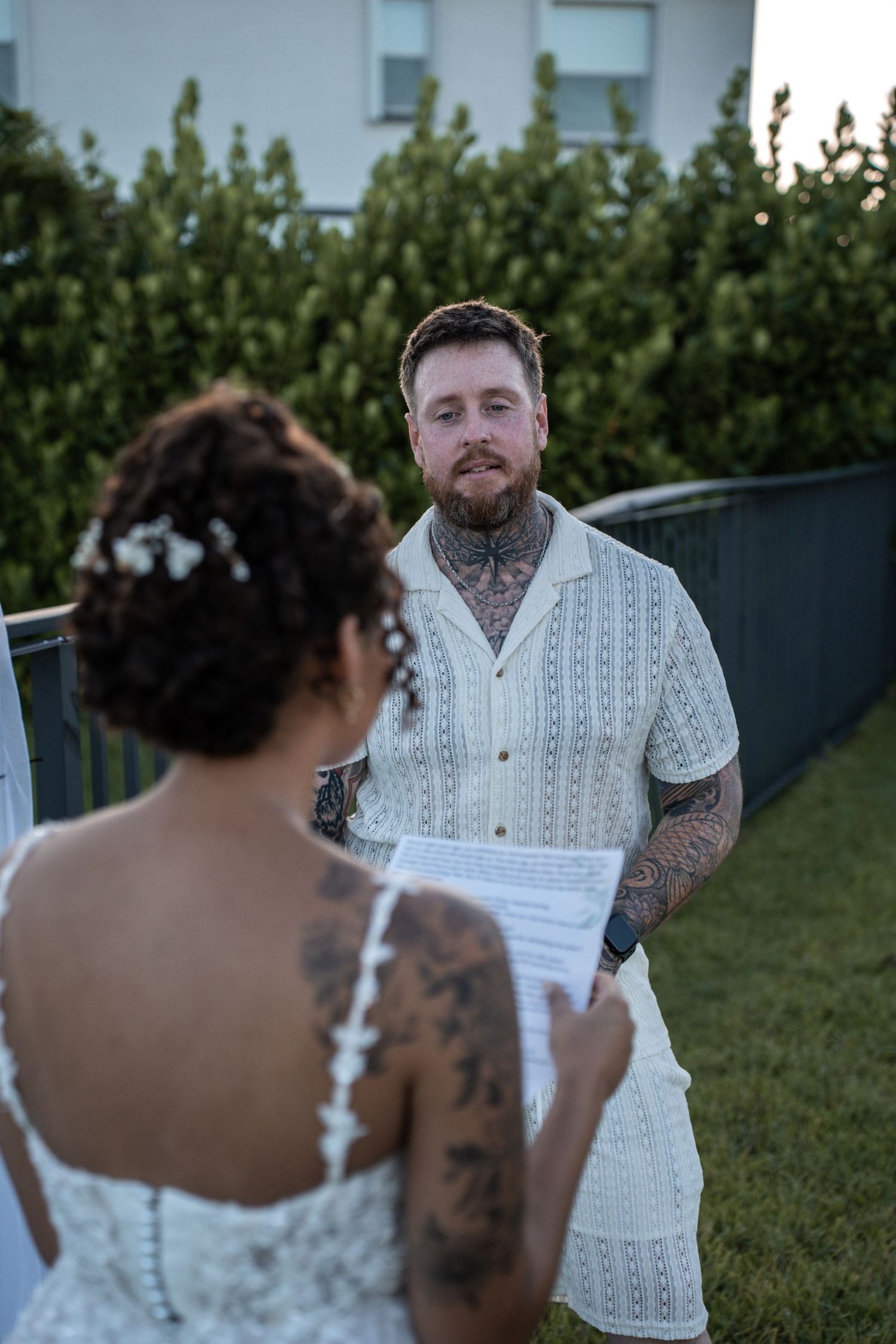 A couple shares an intimate backyard wedding ceremony moment as they read their vows together in the garden.