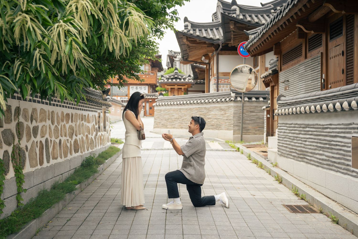 Young couple taking engagement photos at a traditional Korean hanok village in traditional dress.