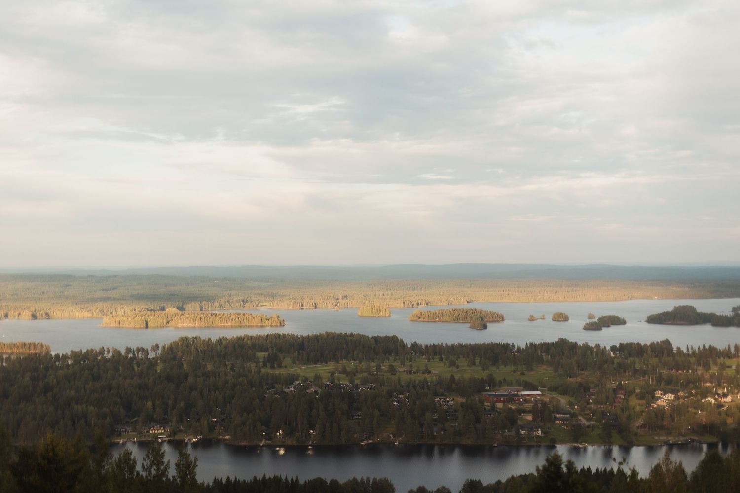 Scenic aerial view of lakes and forests under cloudy skies in a natural landscape.