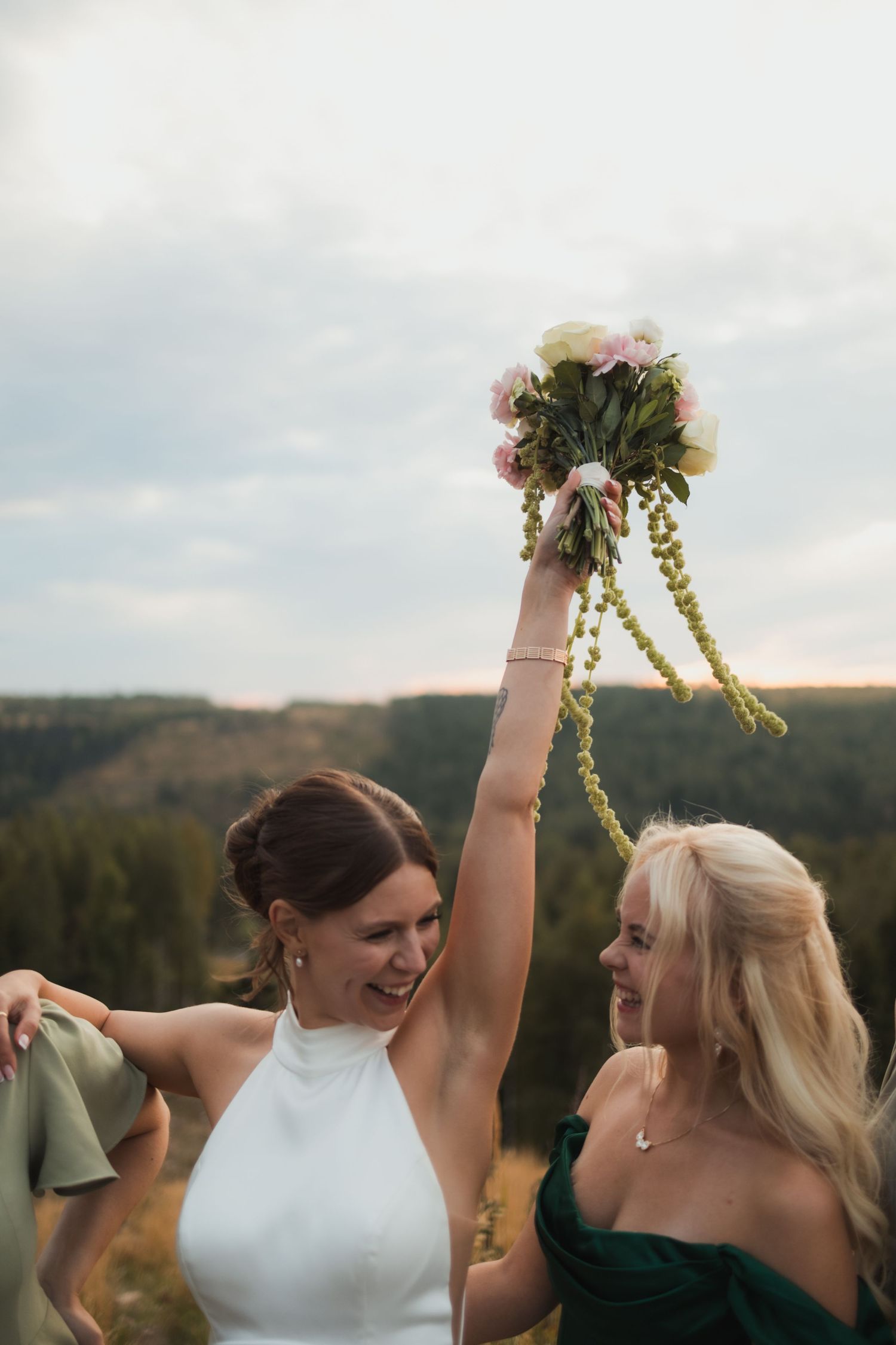 Joyful celebration moment with bouquet held high against mountain landscape at sunset.
