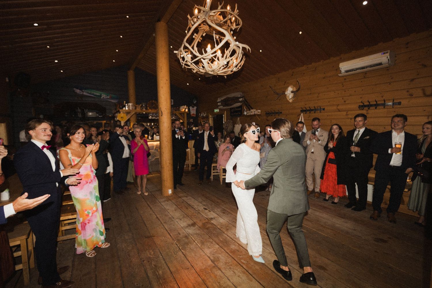 Wedding reception in a rustic wooden barn venue with hanging chandeliers.