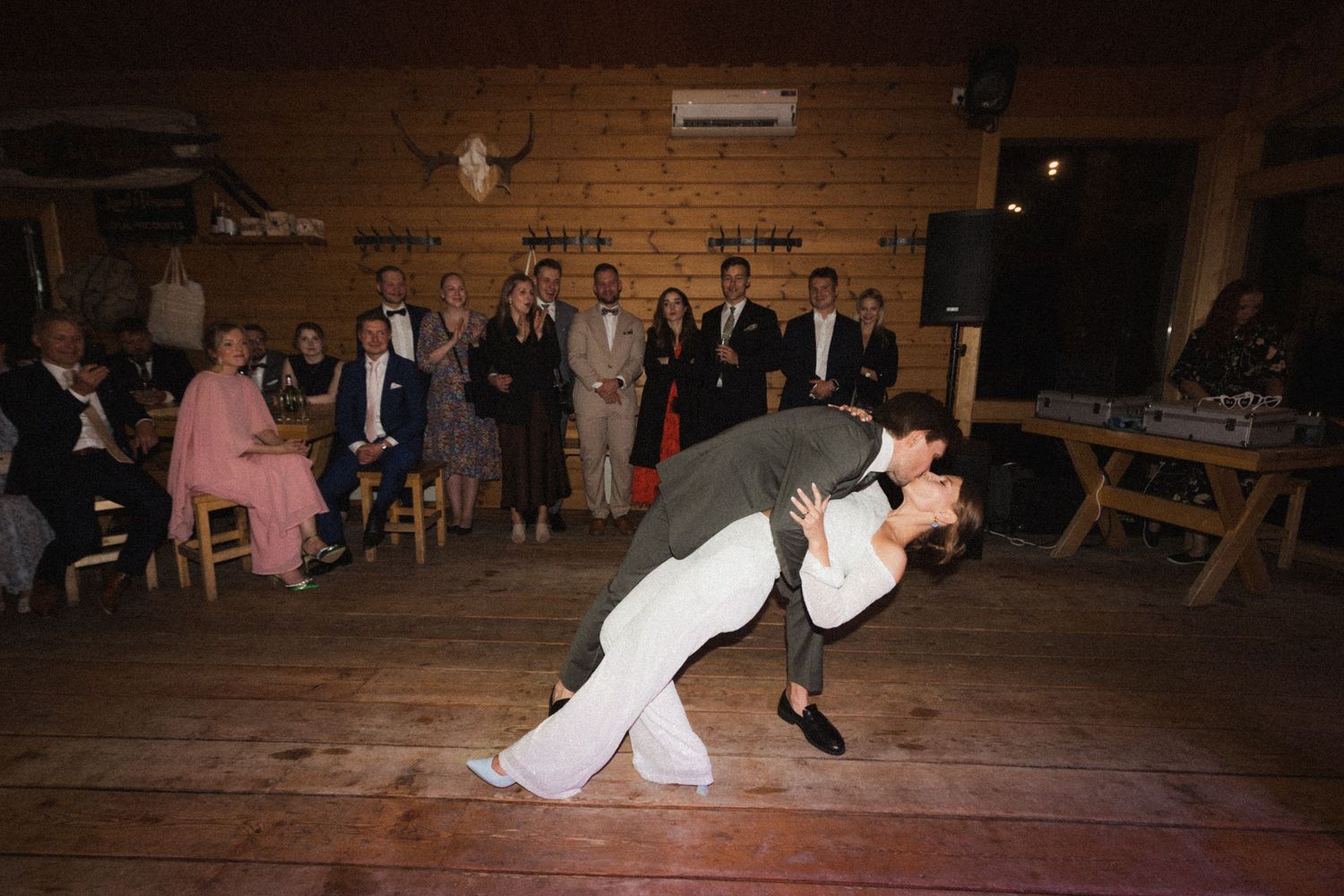 Wedding dance floor scene in a rustic barn venue with guests watching.