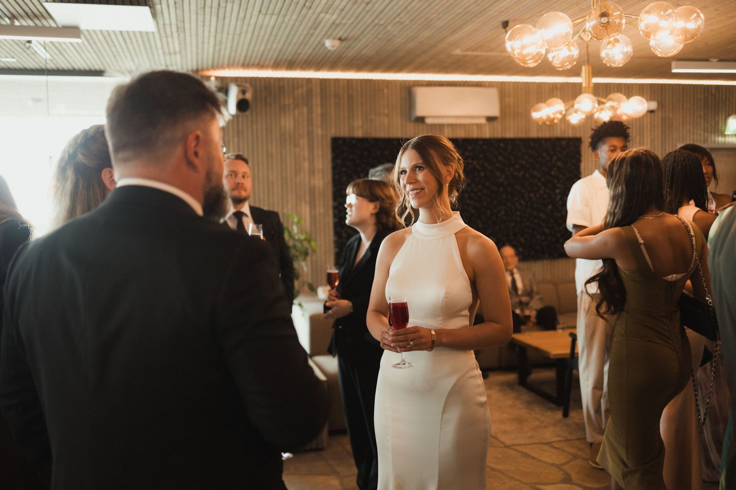 Wedding reception gathering in a modern venue with warm lighting and elegant decor.