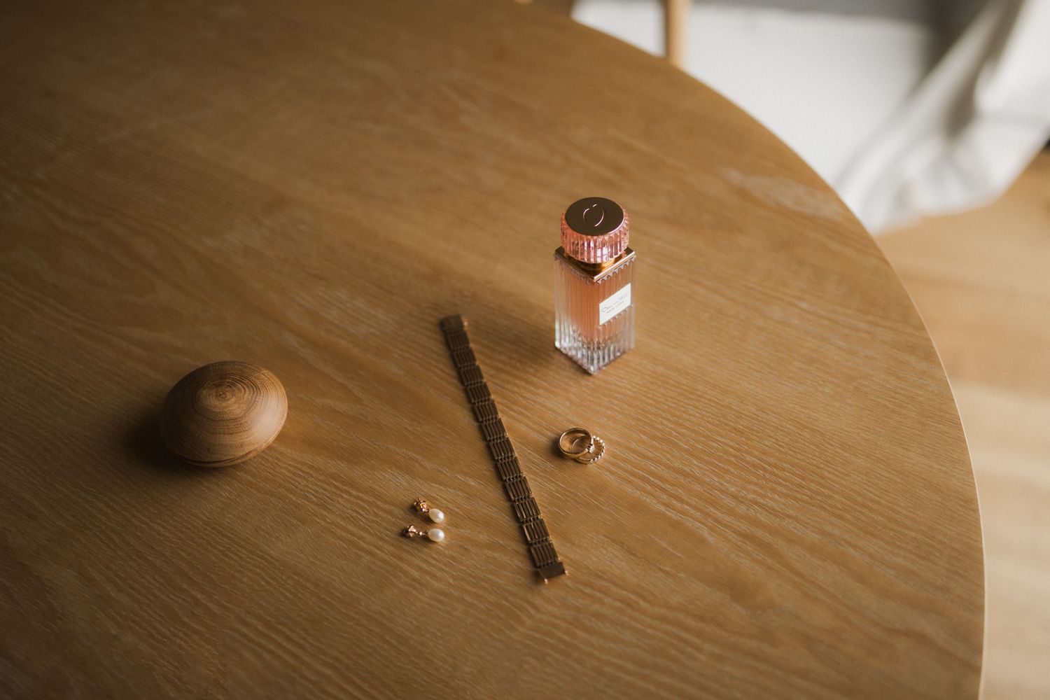 Wedding rings and jewelry arranged on wooden surface in natural light.