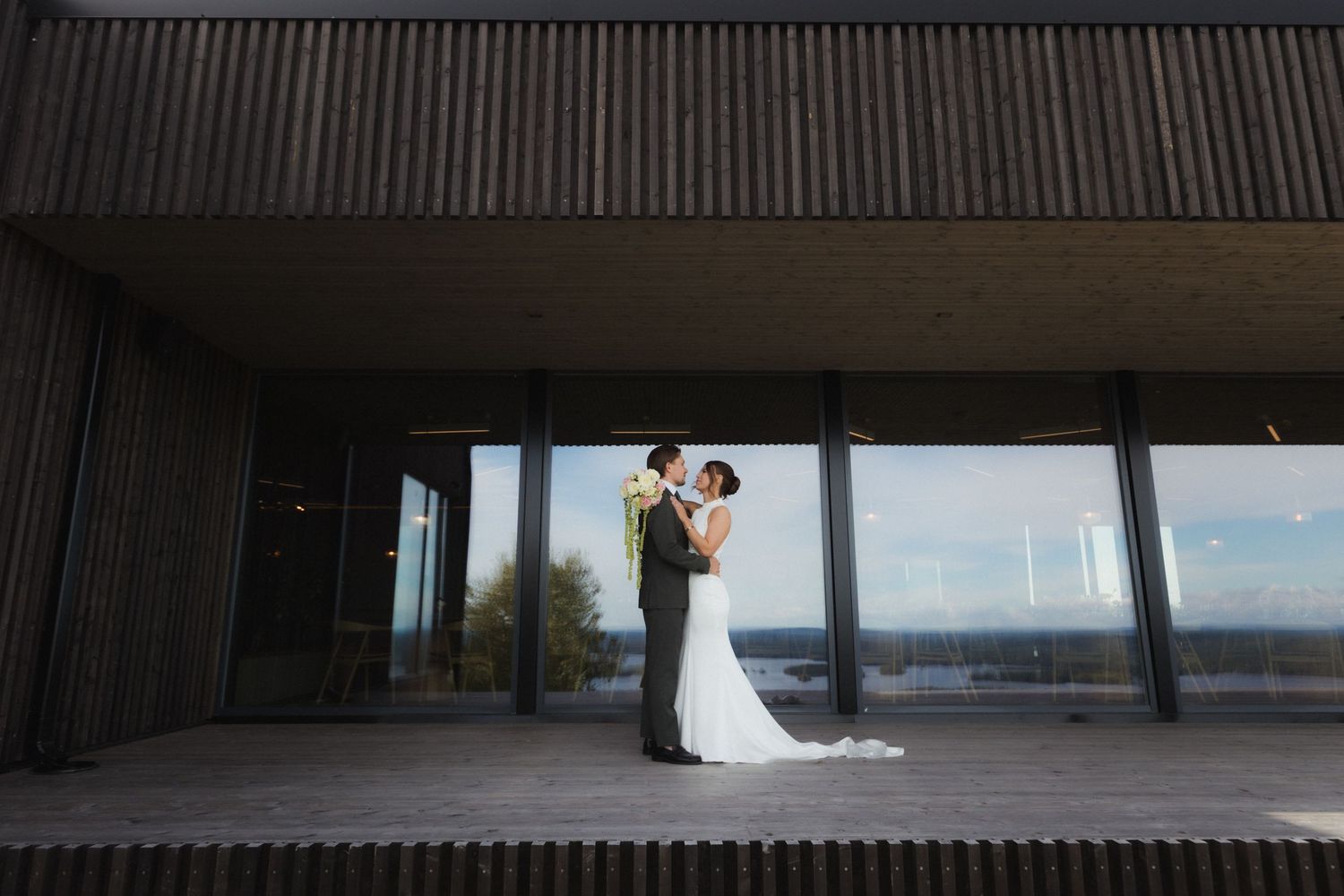 A long covered deck with panoramic windows overlooking a scenic waterfront landscape.