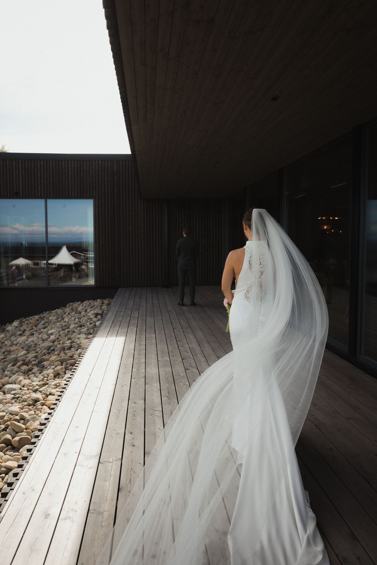 White wedding dress flowing along a modern wooden deck walkway.