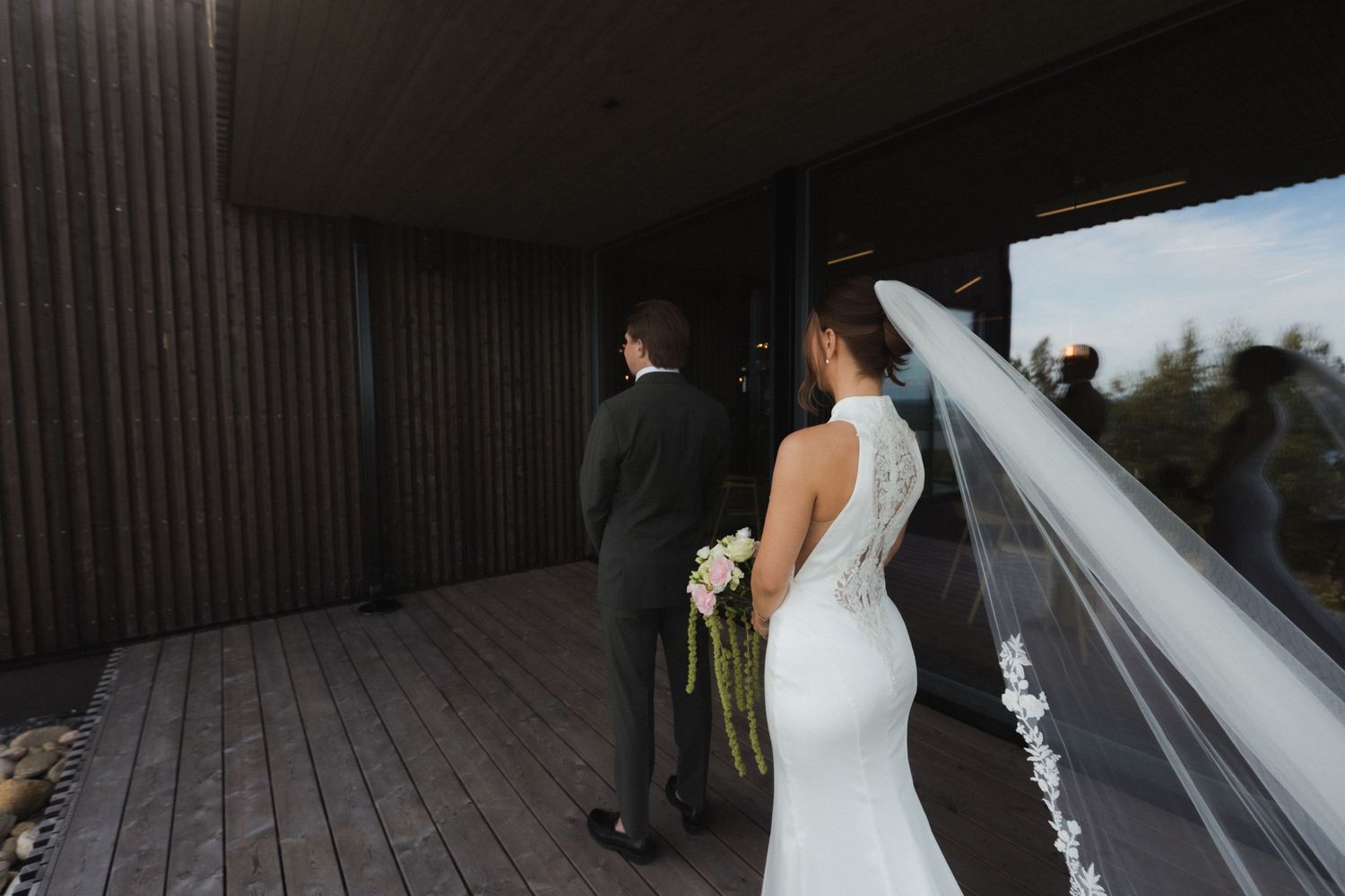 Bride walking along a modern wooden deck with flowing veil and dress.