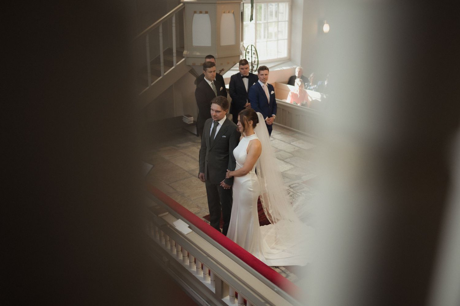 Wedding ceremony processional in a dimly lit church hallway with dramatic shadows.