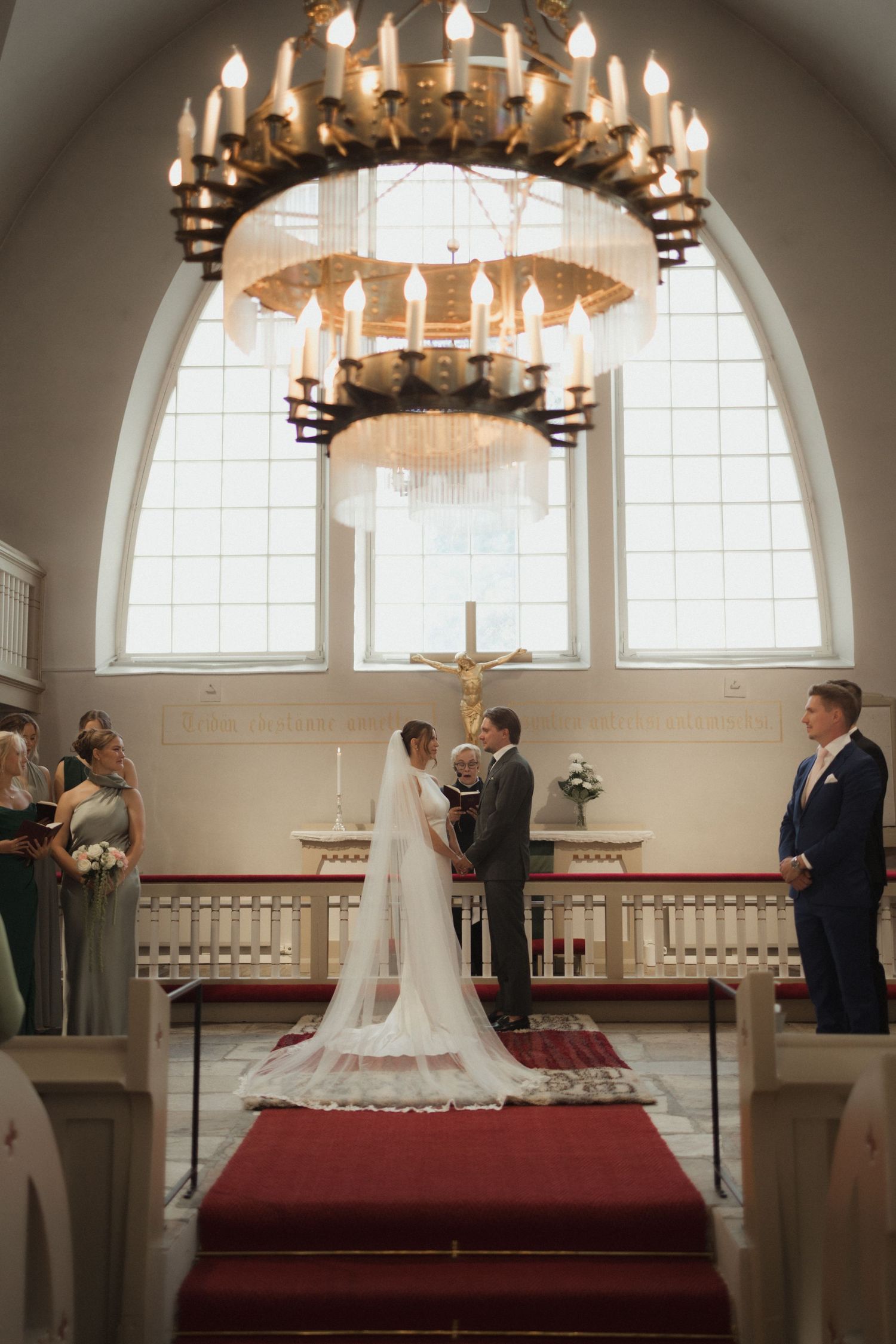 Wedding ceremony in progress under elegant chandeliers in a traditional church sanctuary.