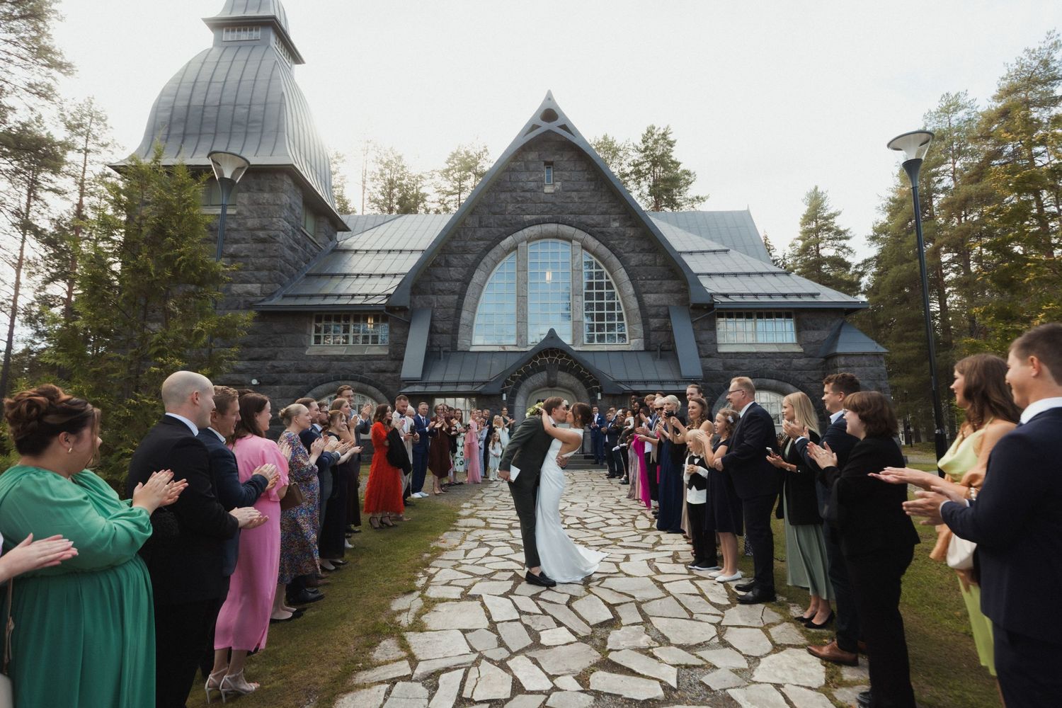 Panoramic view of wedding guests gathered outside a historic chapel.