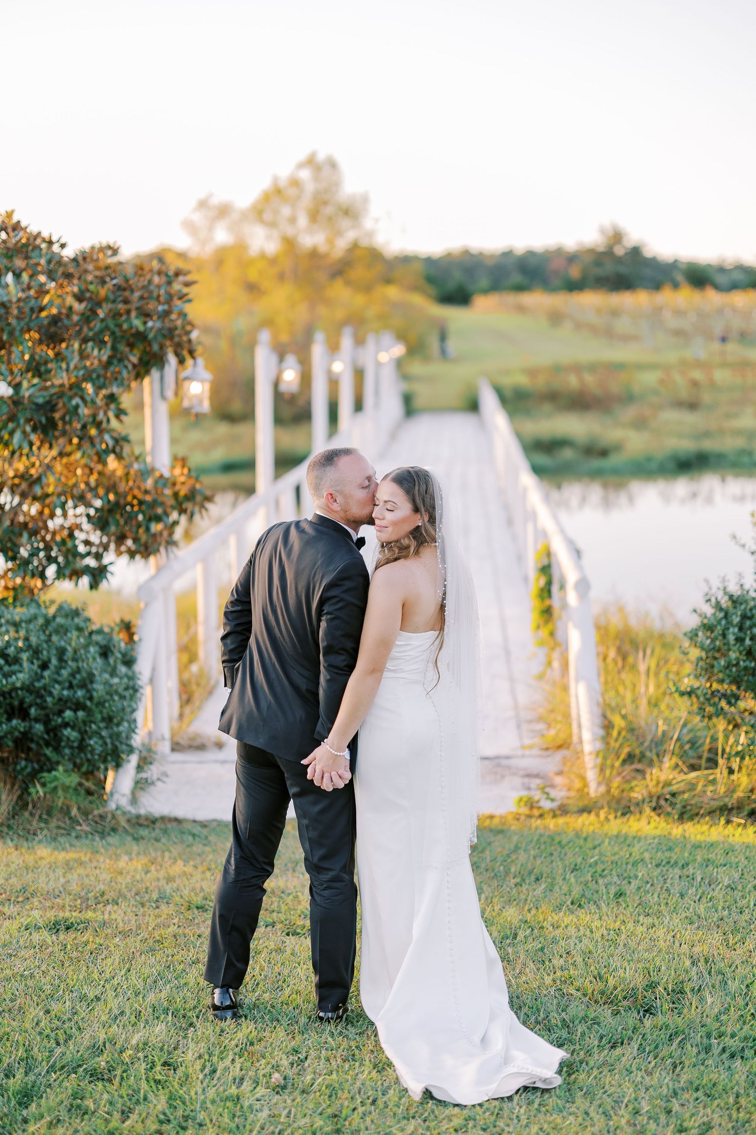 A wedding couple shares an intimate moment in a beautiful outdoor vineyard setting at golden hour.