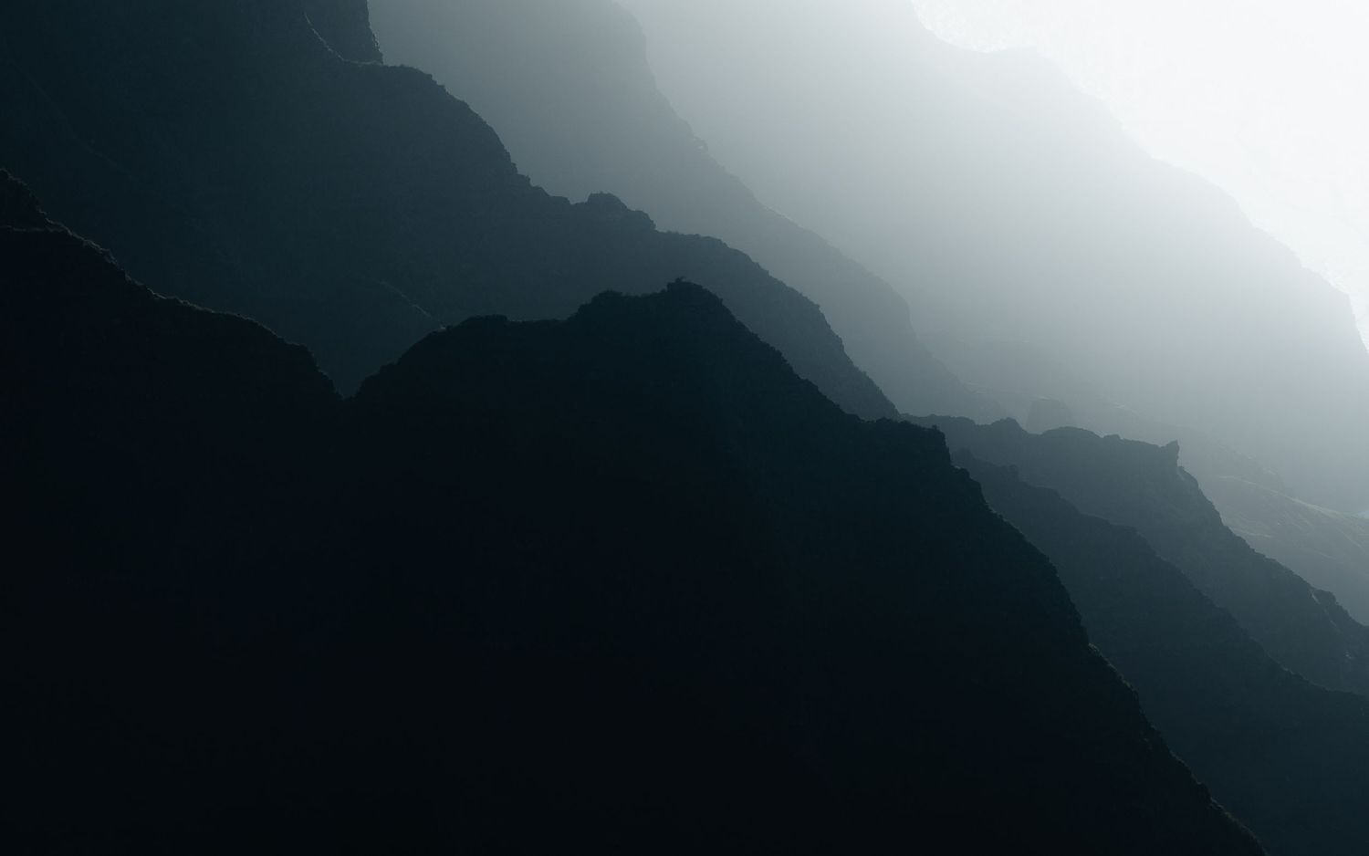 Misty mountain silhouettes fade into foggy layers creating a moody landscape.