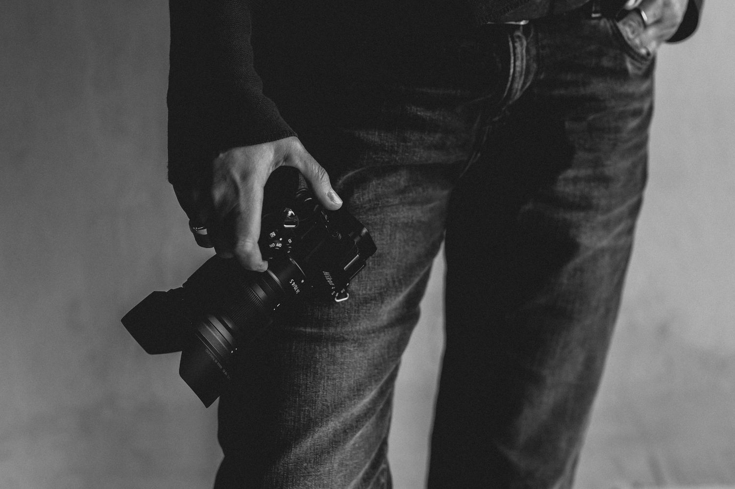 Ein Detailfoto in schwarz-weiß mit einer Kamera in der Hand. Fotografiert im Fotostudio in Gelsenkirchen Hassel.