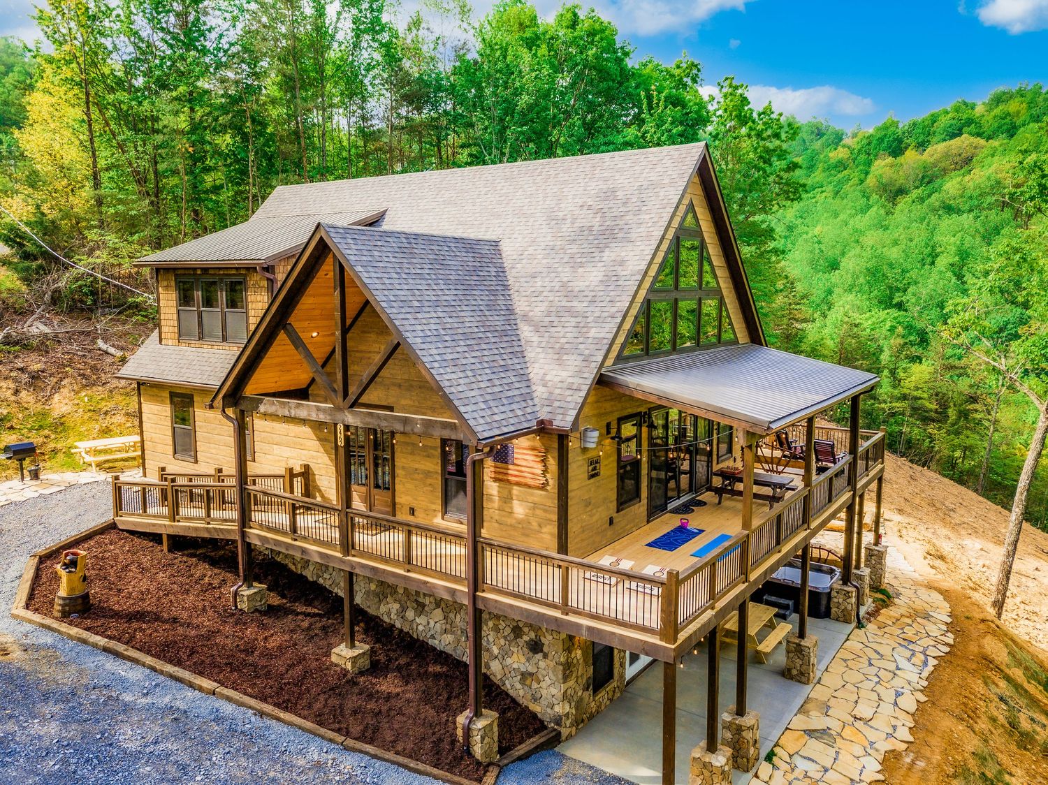 Aerial views of a modern luxury cabin retreat nestled in lush green forest with multiple outdoor decks and large windows.