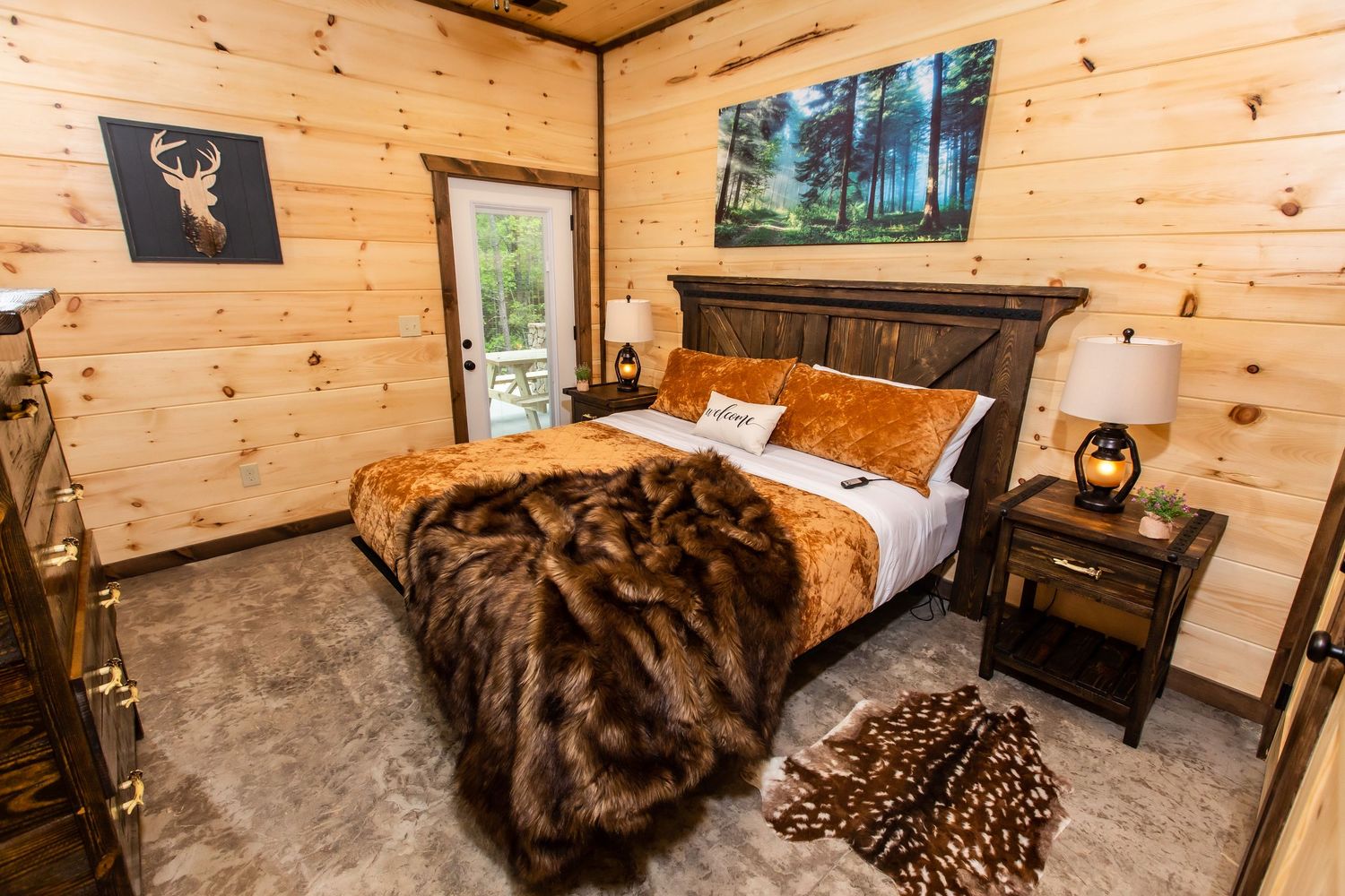 Spacious cabin bedroom with pine walls, rustic furnishings, and plush bedding in earth tones.