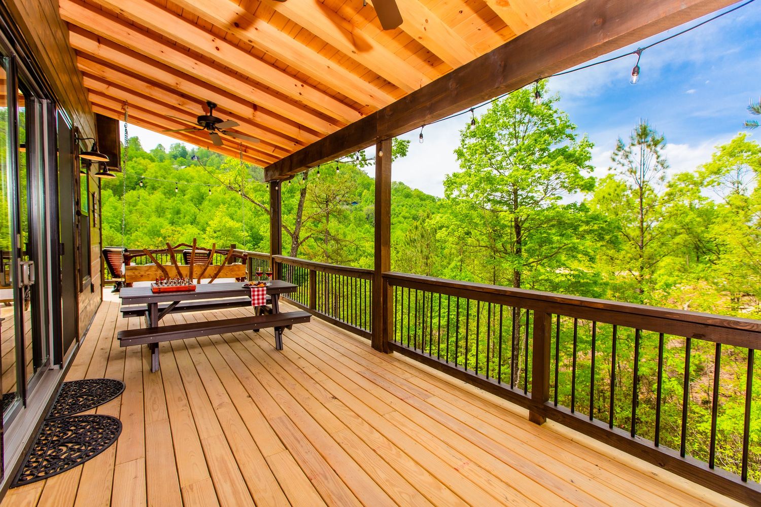 Covered deck with wooden ceiling beams and panoramic forest views in natural setting.