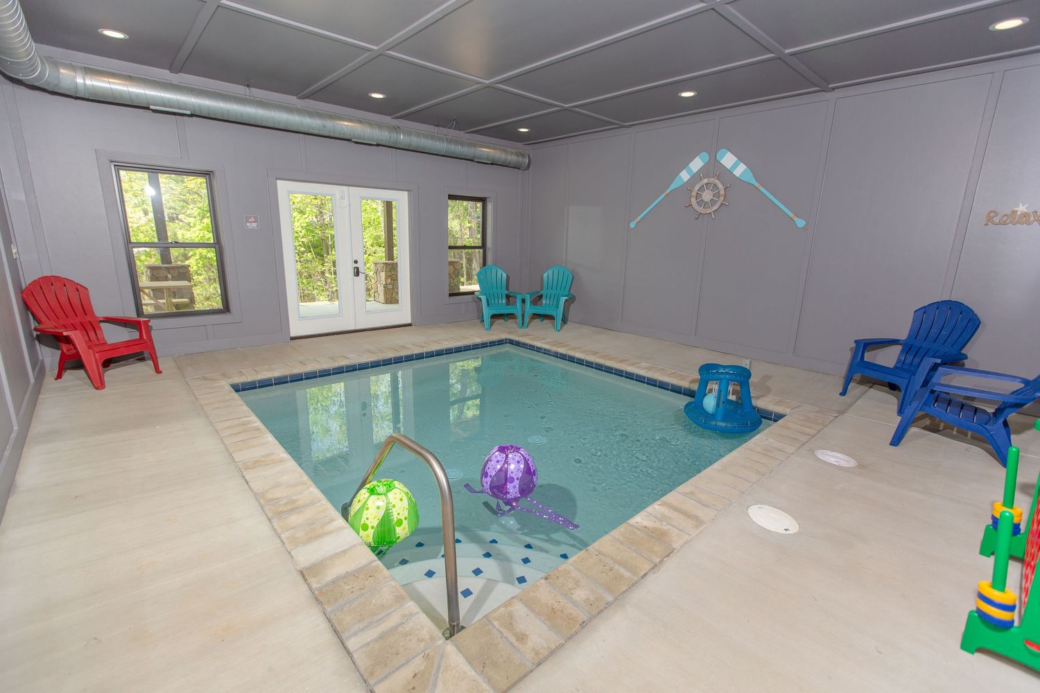 Modern game room with colorful Adirondack chairs and entertainment setup.