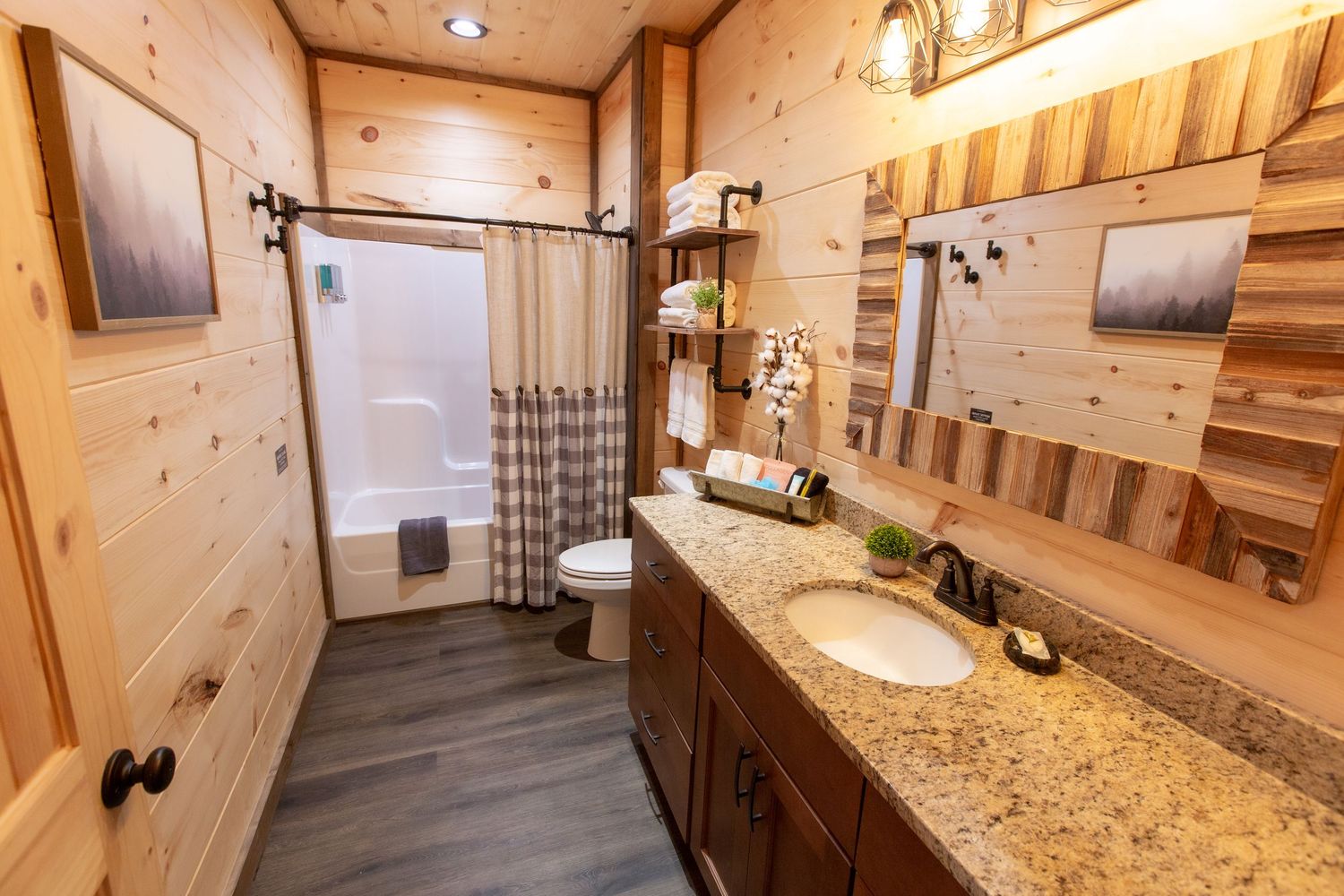 Modern bathroom interior with wood paneling, granite countertops and rustic light fixtures.
