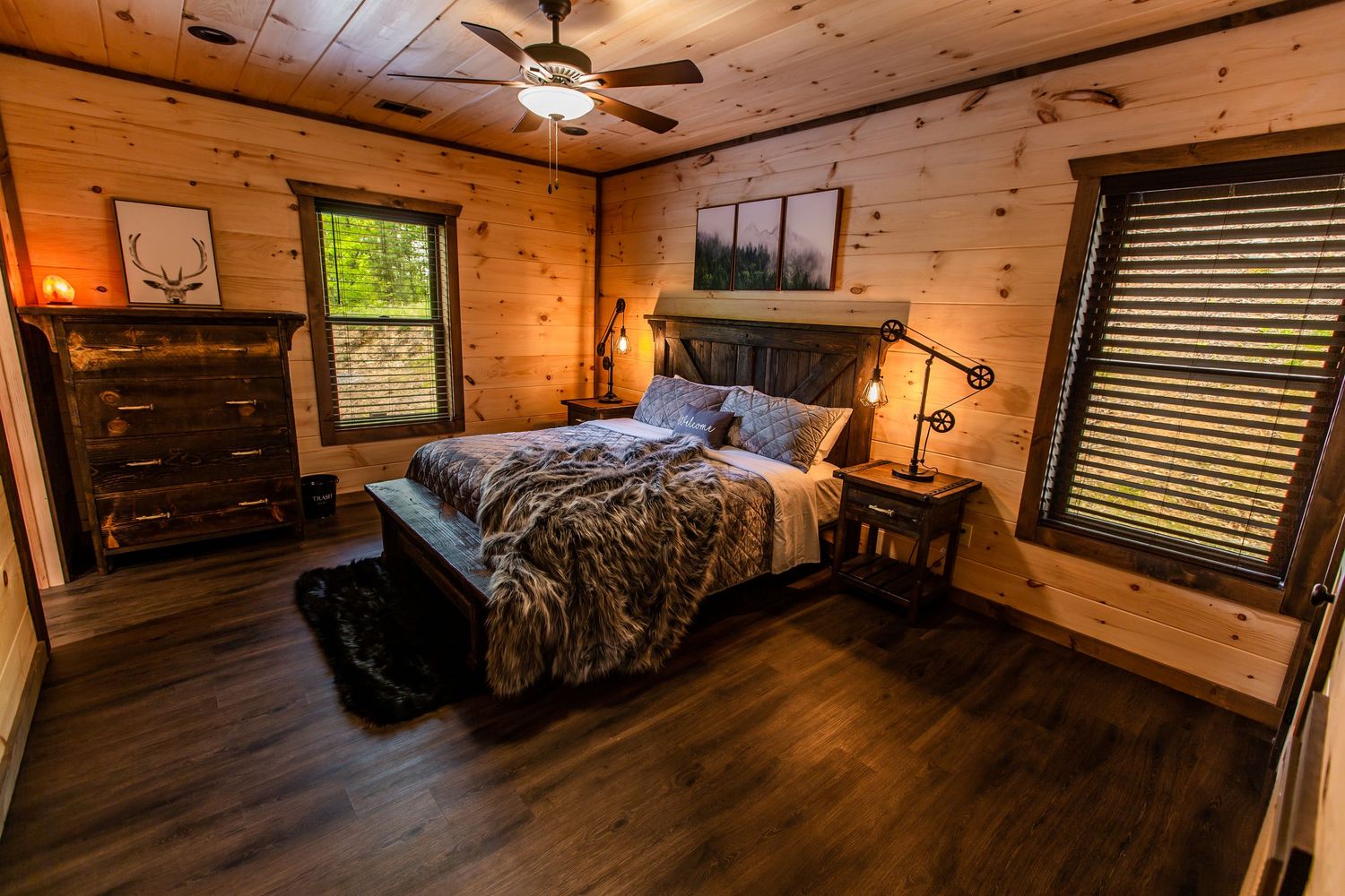 Interior panorama of a cozy log cabin bedroom with wood paneled walls and warm lighting.