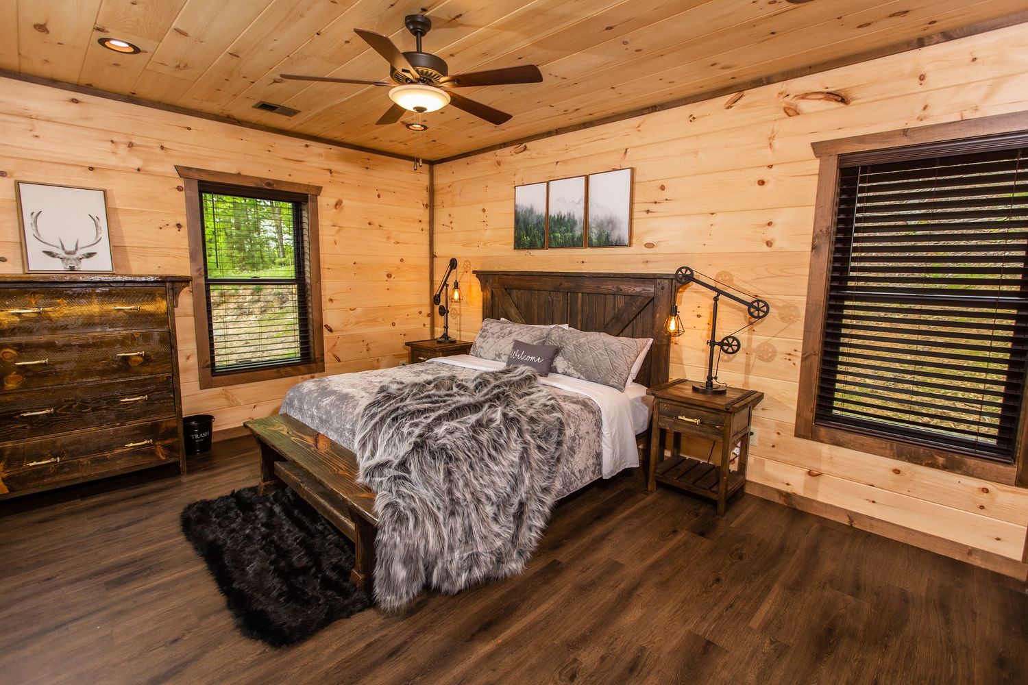 Cozy log cabin bedroom interior with wooden walls, ceiling fan, and rustic decor showcasing warm lighting and hardwood floors.