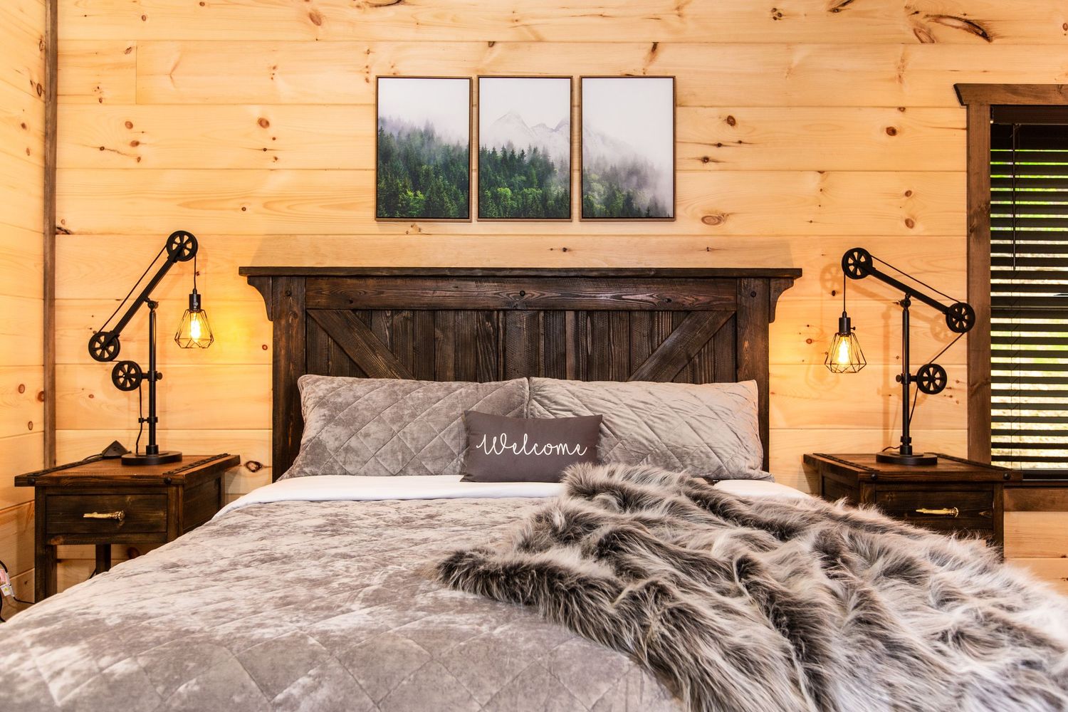 A cozy rustic cabin interior with wooden walls, exposed beams, and warm lighting fixtures mounted along the walls.