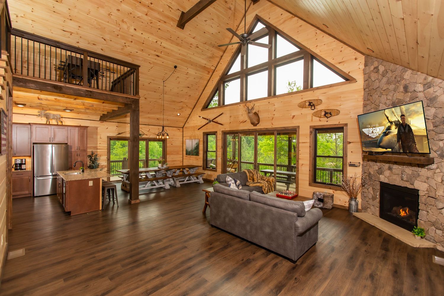 Spacious cabin living room with vaulted ceiling, wood beams, and comfortable gray sectional sofa.
