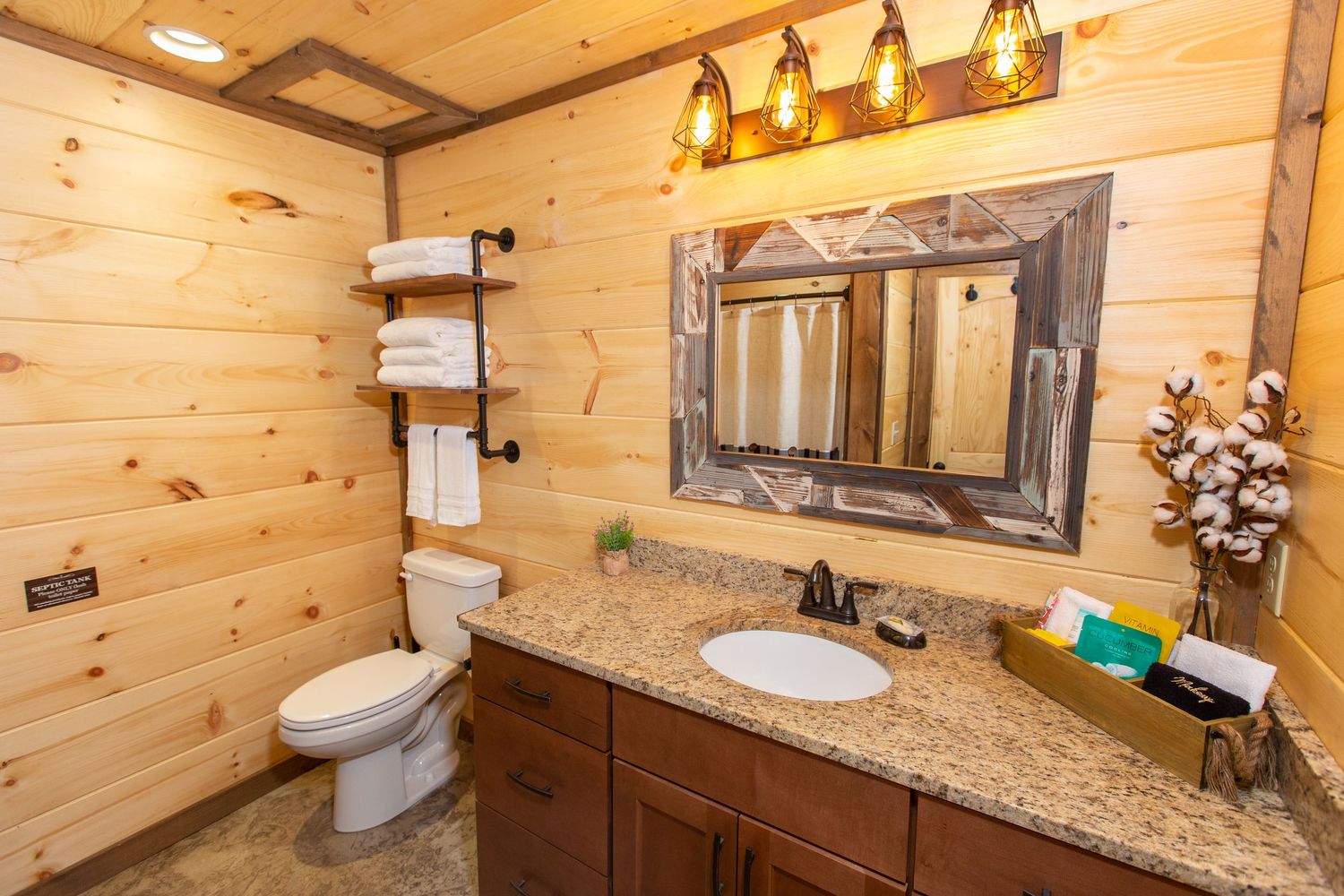Rustic bathroom featuring wood walls, granite countertop, and decorative pendant lighting.