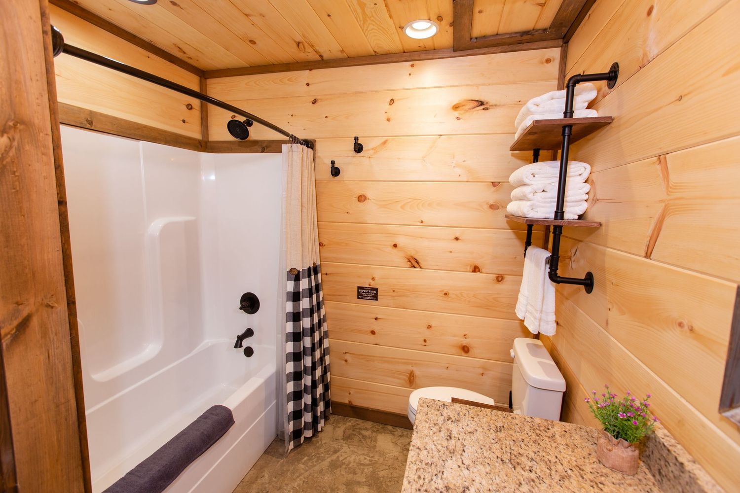 Luxurious bathroom with white tiled shower and wooden walls in rustic cabin style.