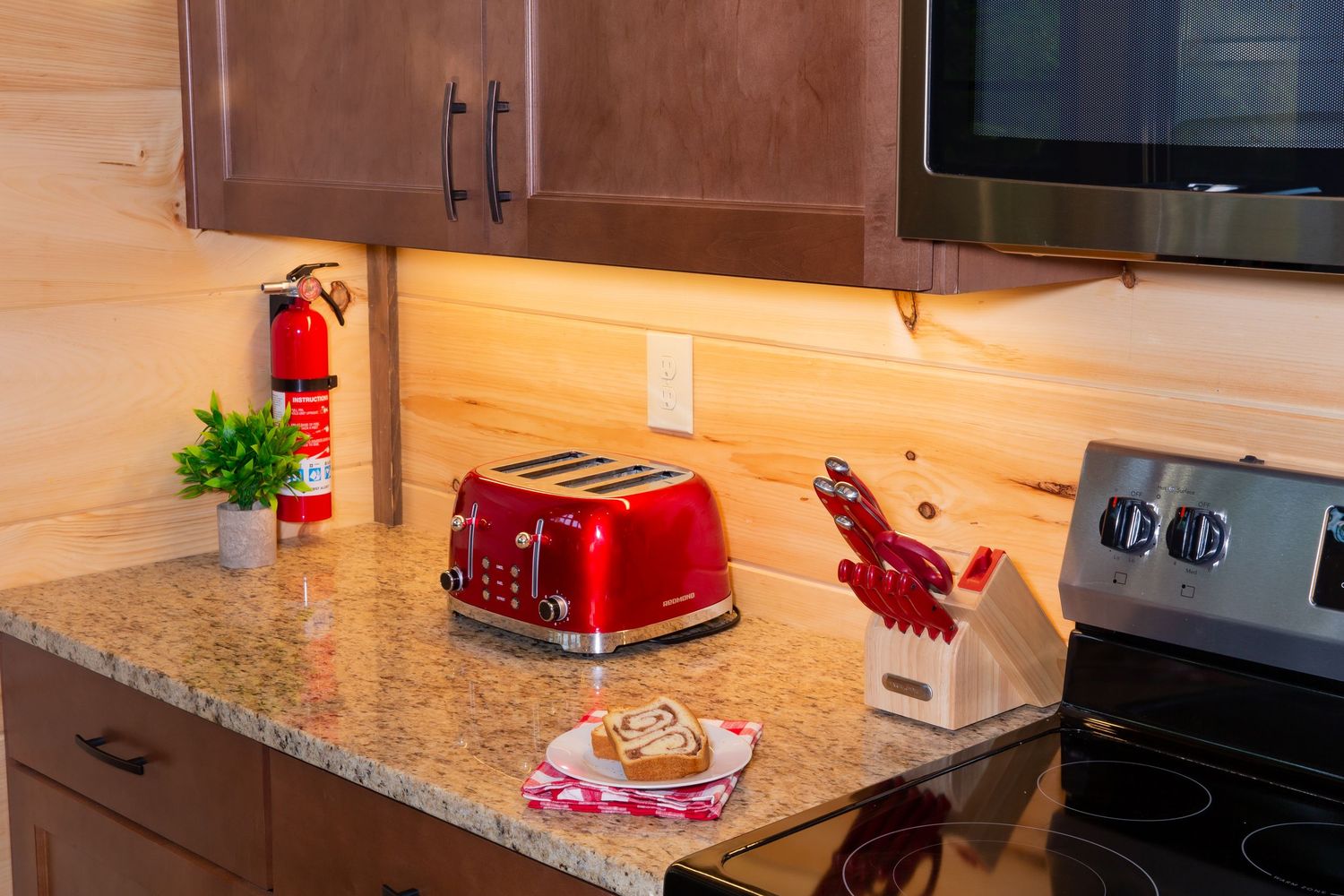 Modern kitchen interior with wooden cabinets, granite countertops, and red appliances showcases contemporary design.