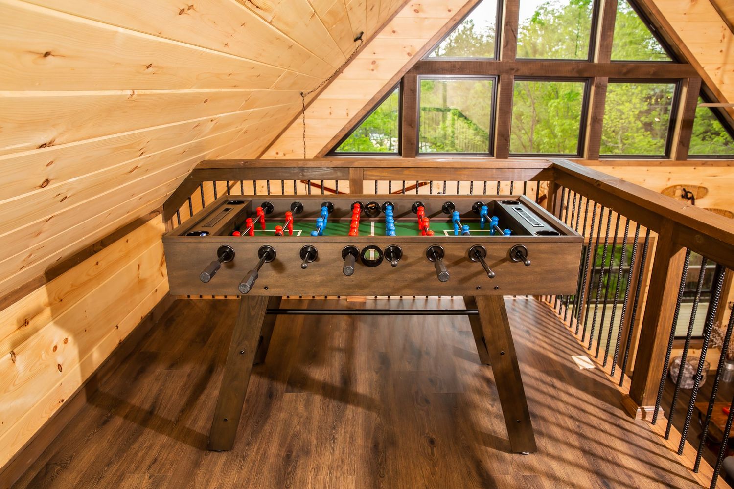 Interior view of a rustic wooden cabin loft with exposed beams and natural lighting through windows.