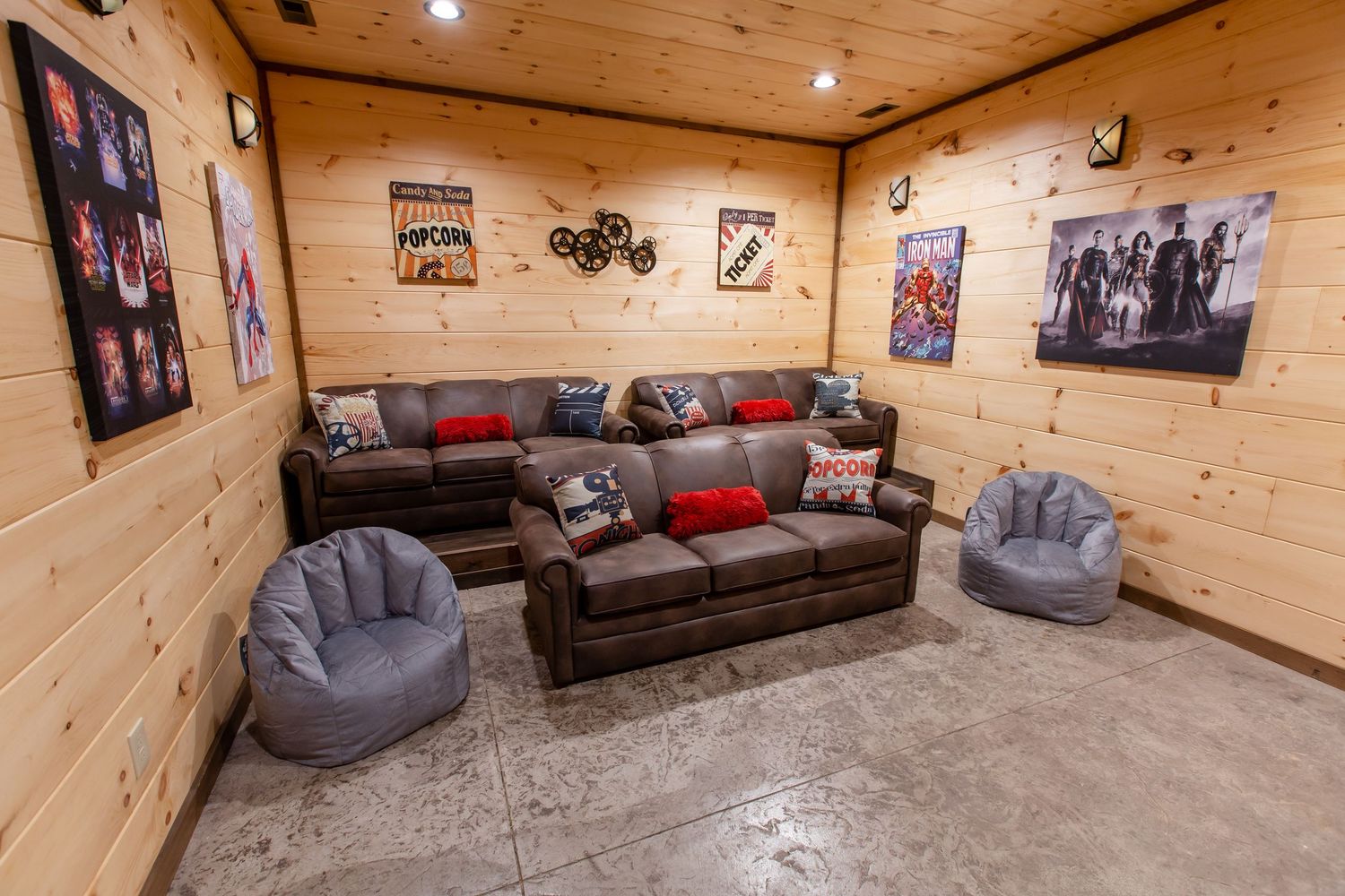 Cozy log cabin interior with wood paneled walls, recessed lighting, and comfortable gray and brown furniture.